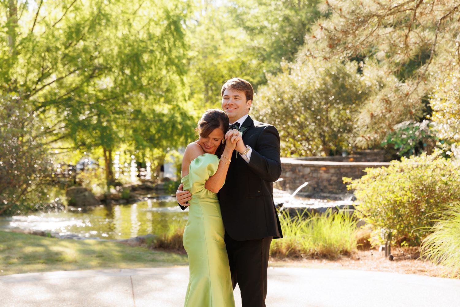 Couple sharing a romantic dance outdoors, woman in green gown embraced by man in black suit.