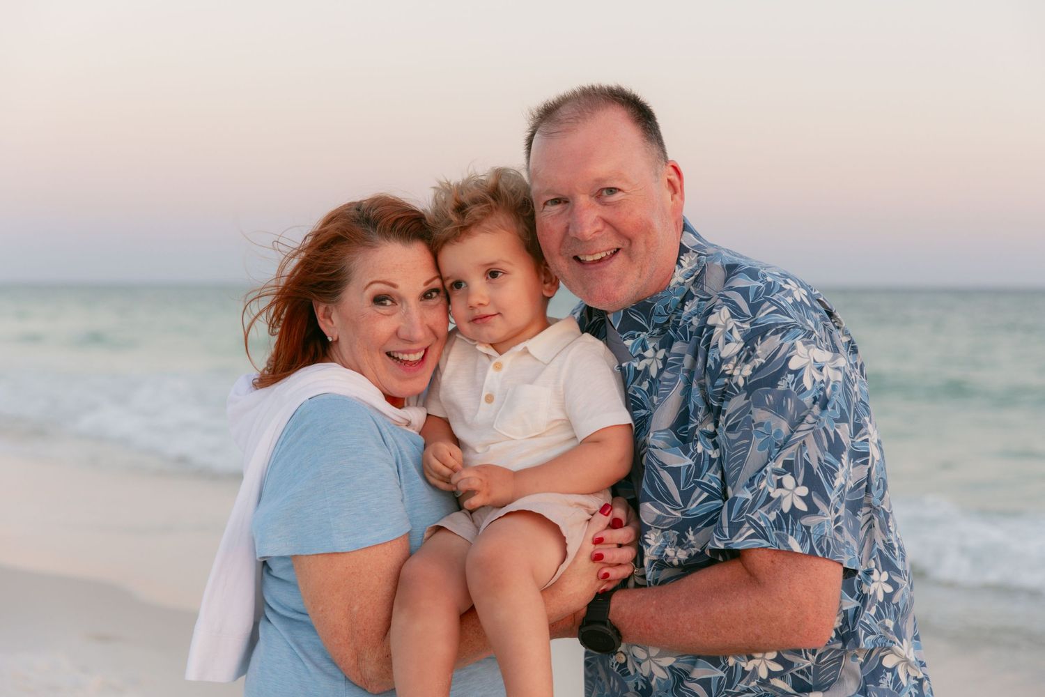 Family portrait at sunset on beach with ocean backdrop.