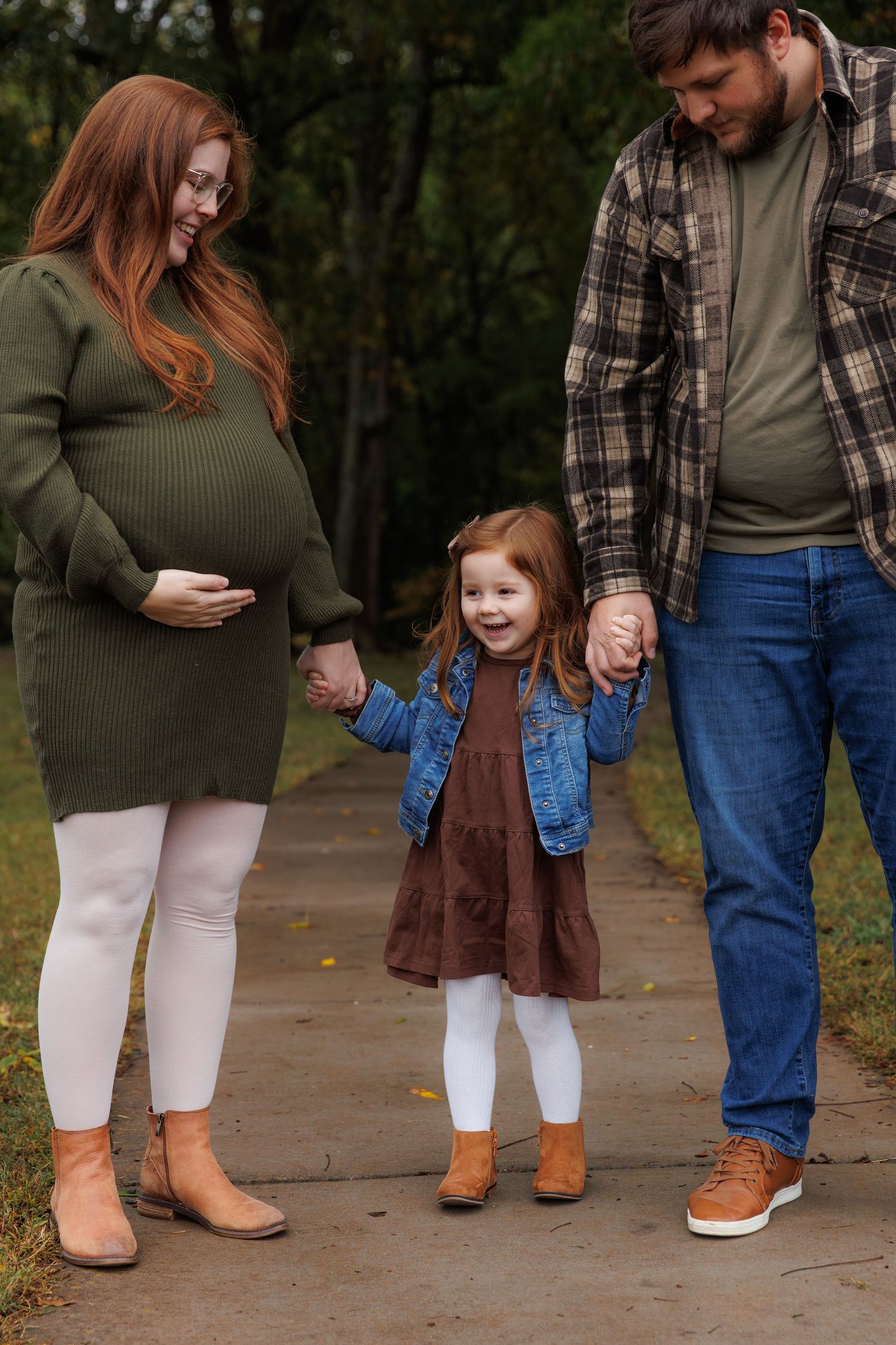 Family wearing coordinated fall outfits with plaid and earth tones walking together on a path in nature.