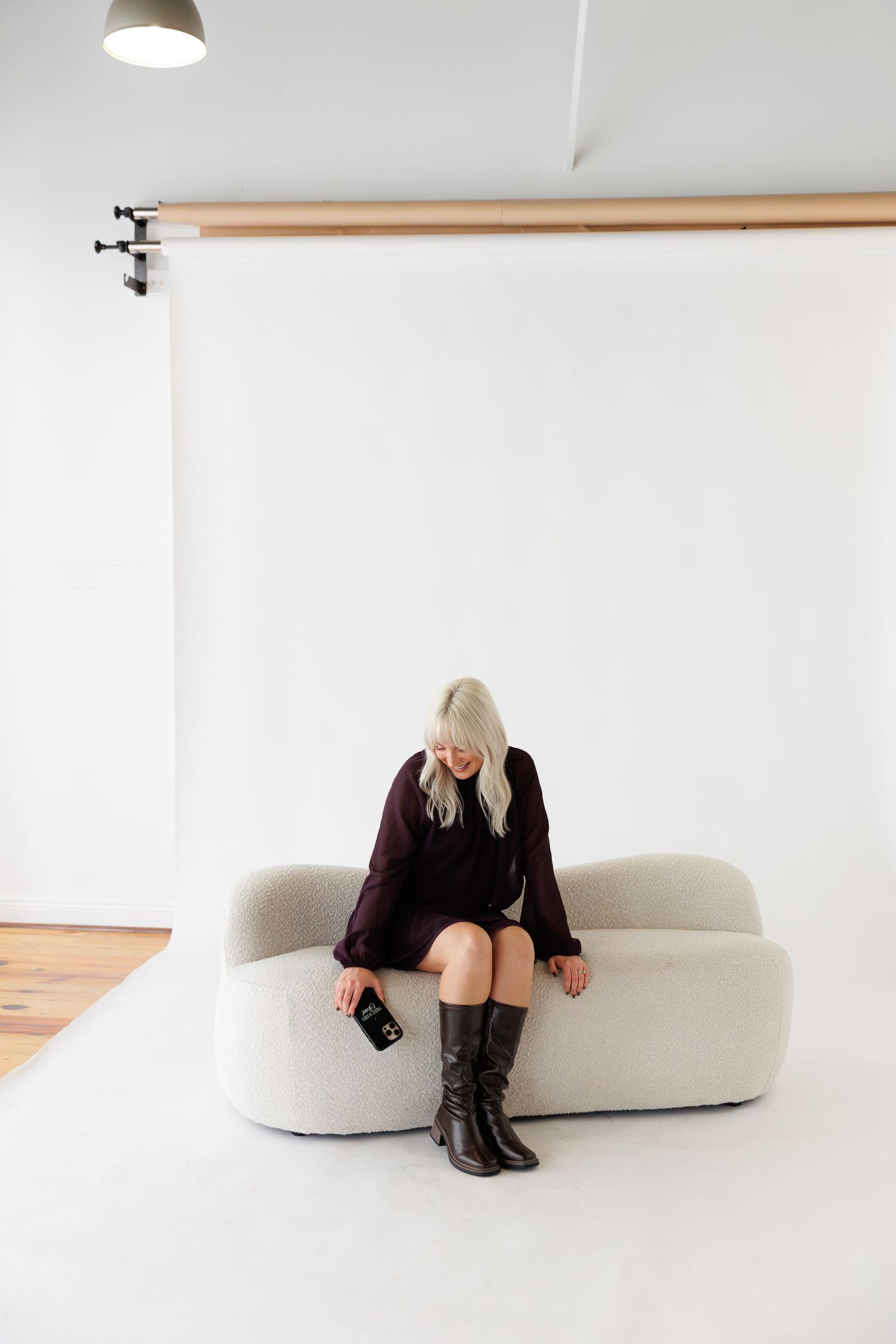 Person wearing dark outfit relaxes on sculptural white seating in bright studio environment.