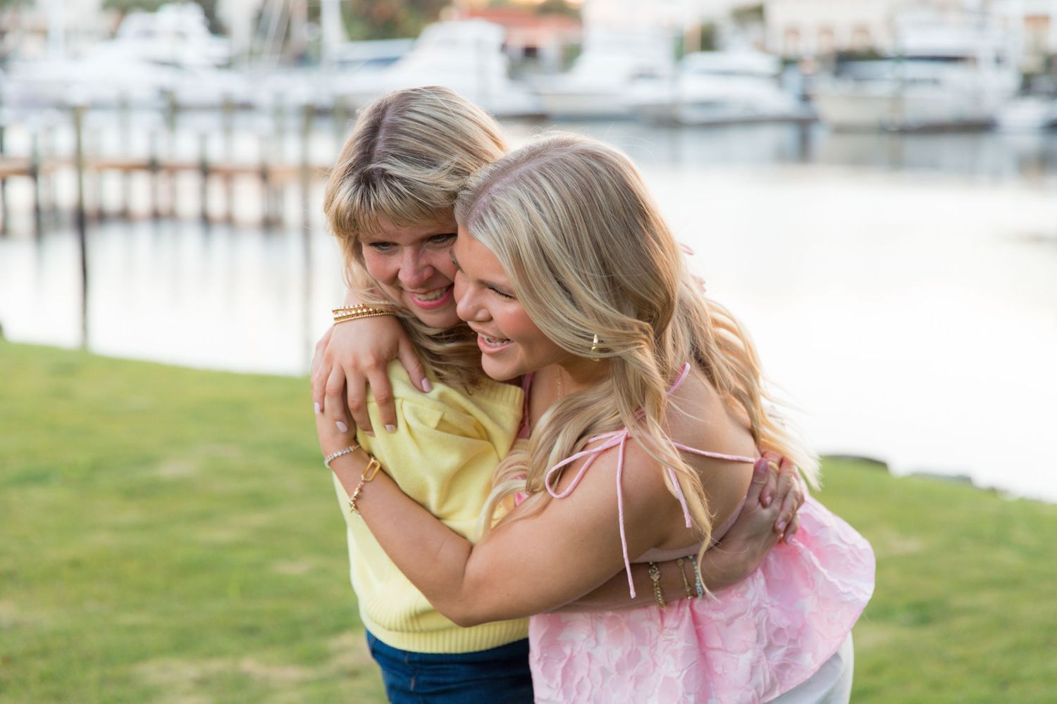 A couple in casual attire shares an intimate moment while sitting together on a dock by the water.