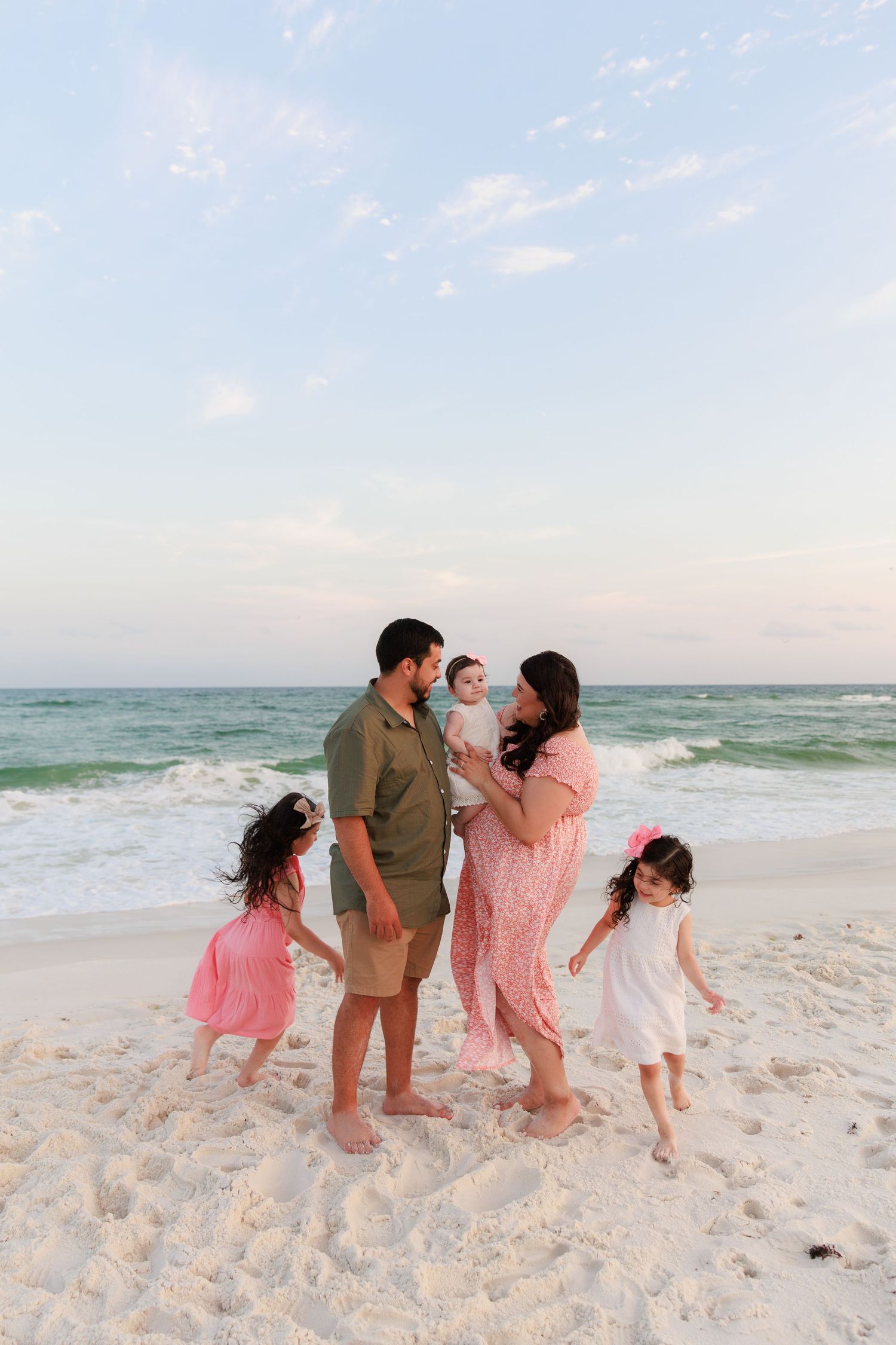 Family of five enjoying a sunset beach photoshoot on white sand shores with turquoise ocean waves.