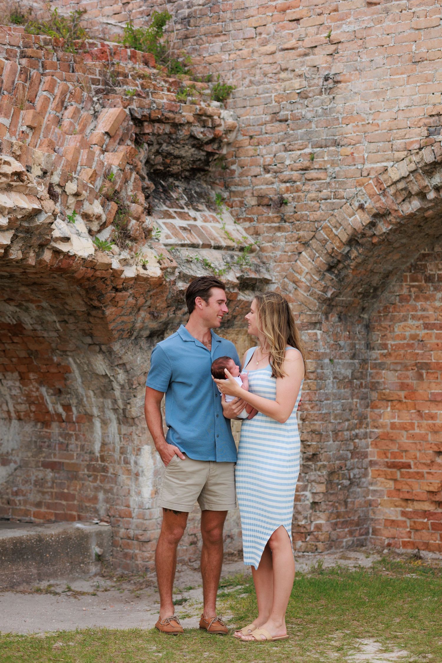A couple shares intimate moments against a rustic brick wall backdrop in a romantic outdoor setting.