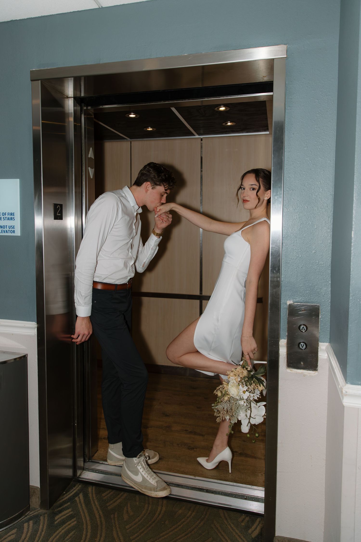 A sequence of four photos showing a couple playfully posing near an elevator in white wedding attire.
