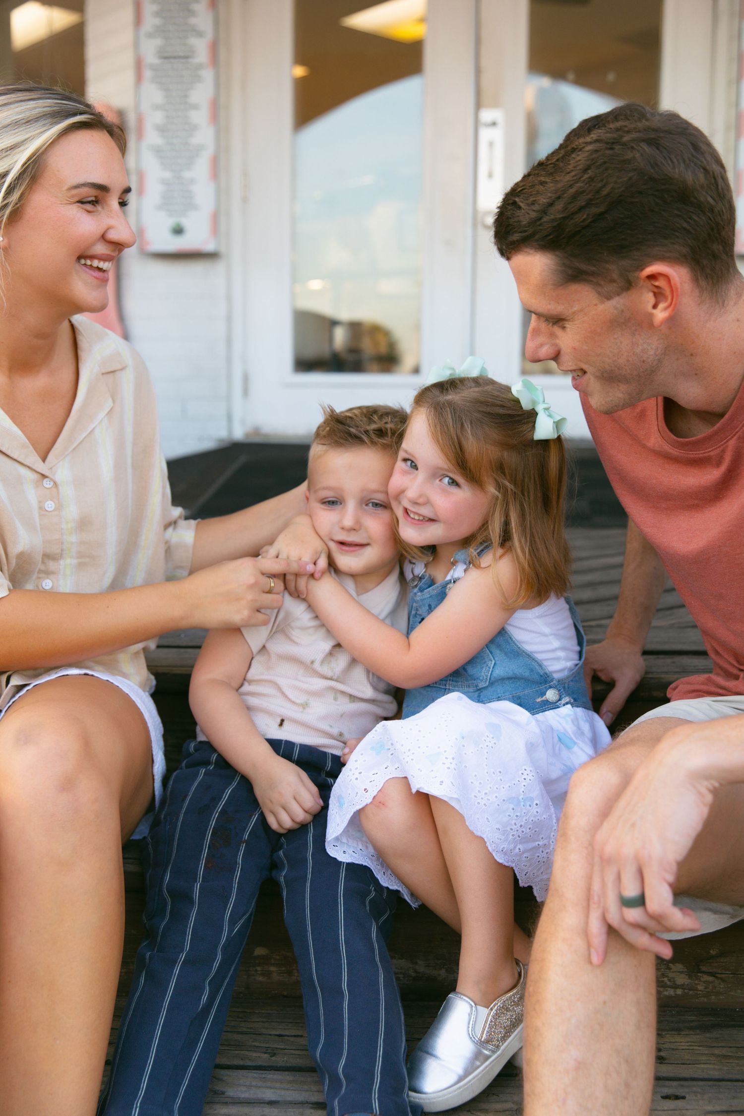 A sweet family moment shared on wooden steps outside an ice cream shop.