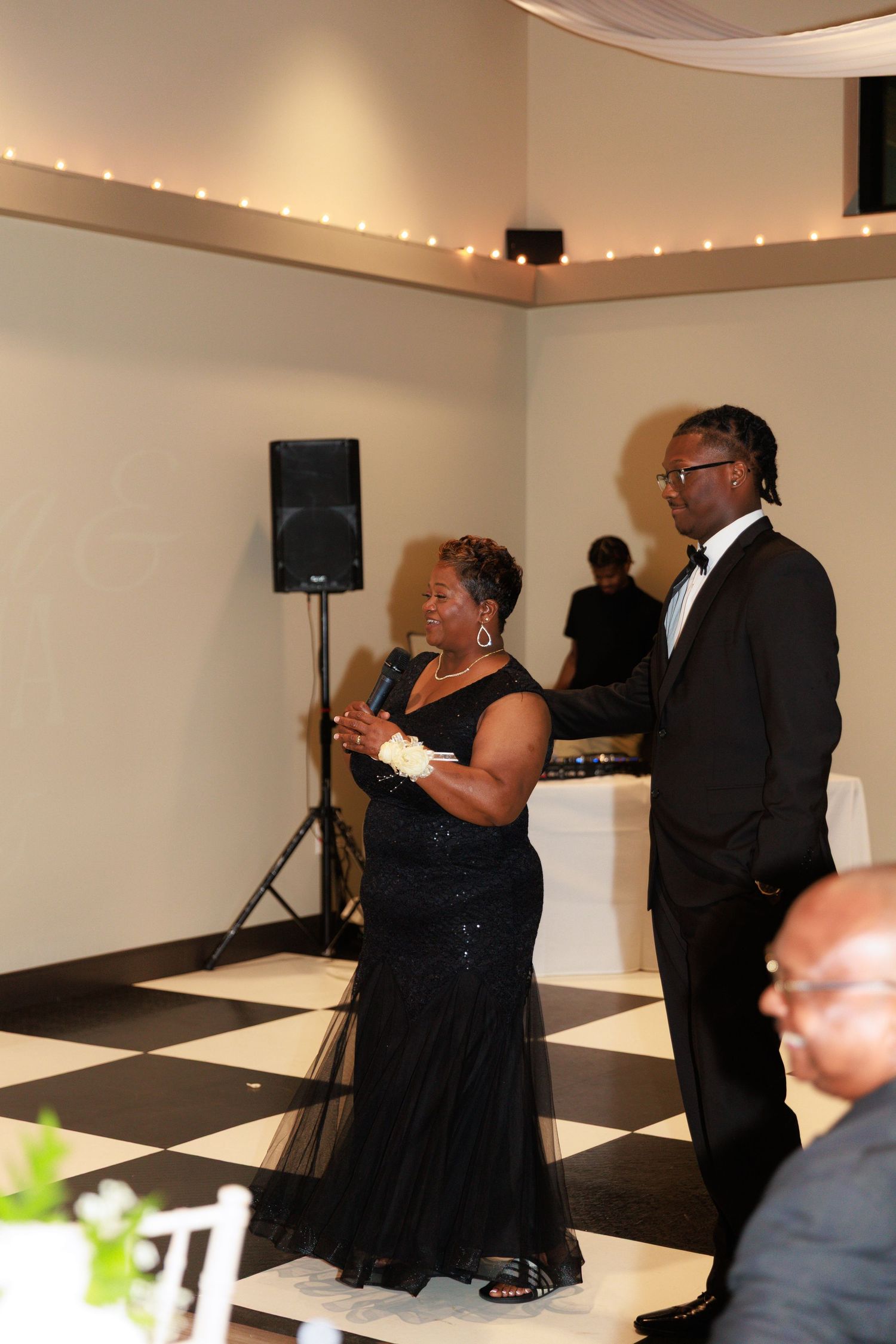 Wedding guests dance and celebrate on a black and white checkered dance floor.