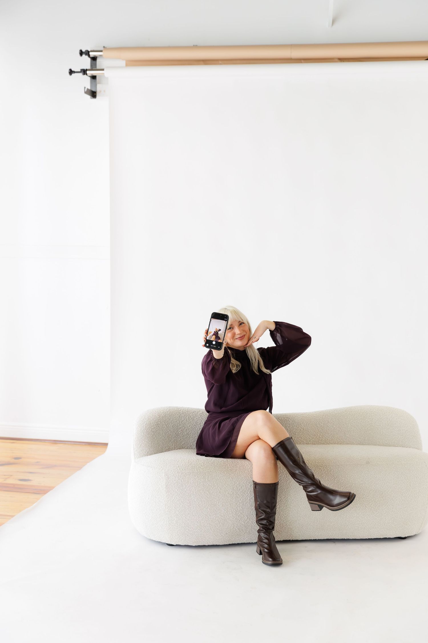 Individual in dark attire reclines on modern white furniture piece in clean studio setting.