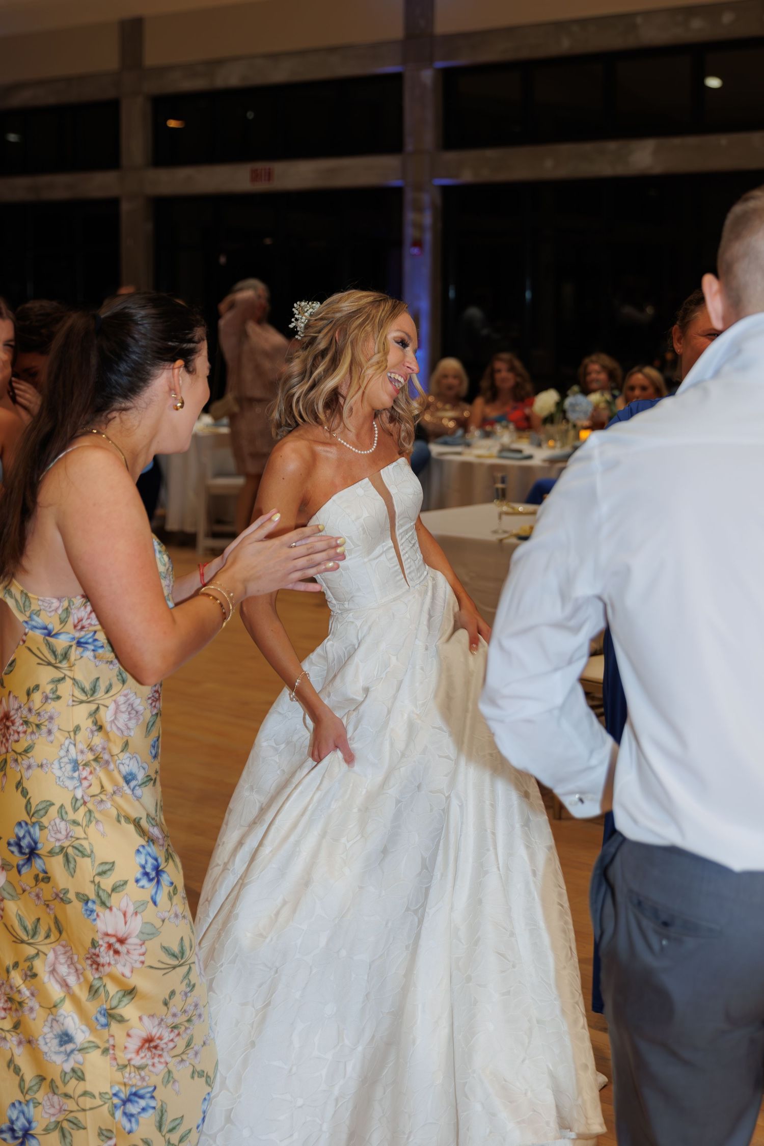A bride in a white ballgown dancing at her wedding reception on a wooden floor.