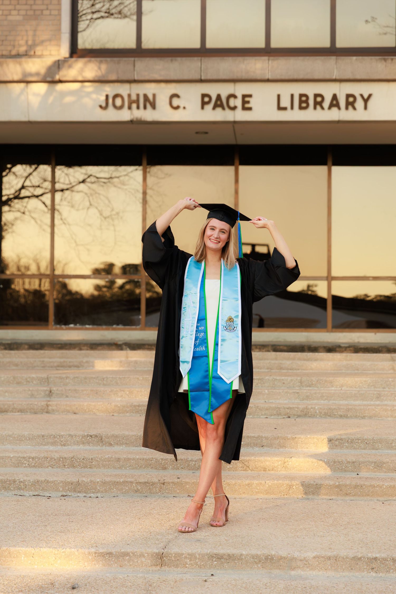 Graduation photos captured on the steps of John C. Pace Library during golden hour.