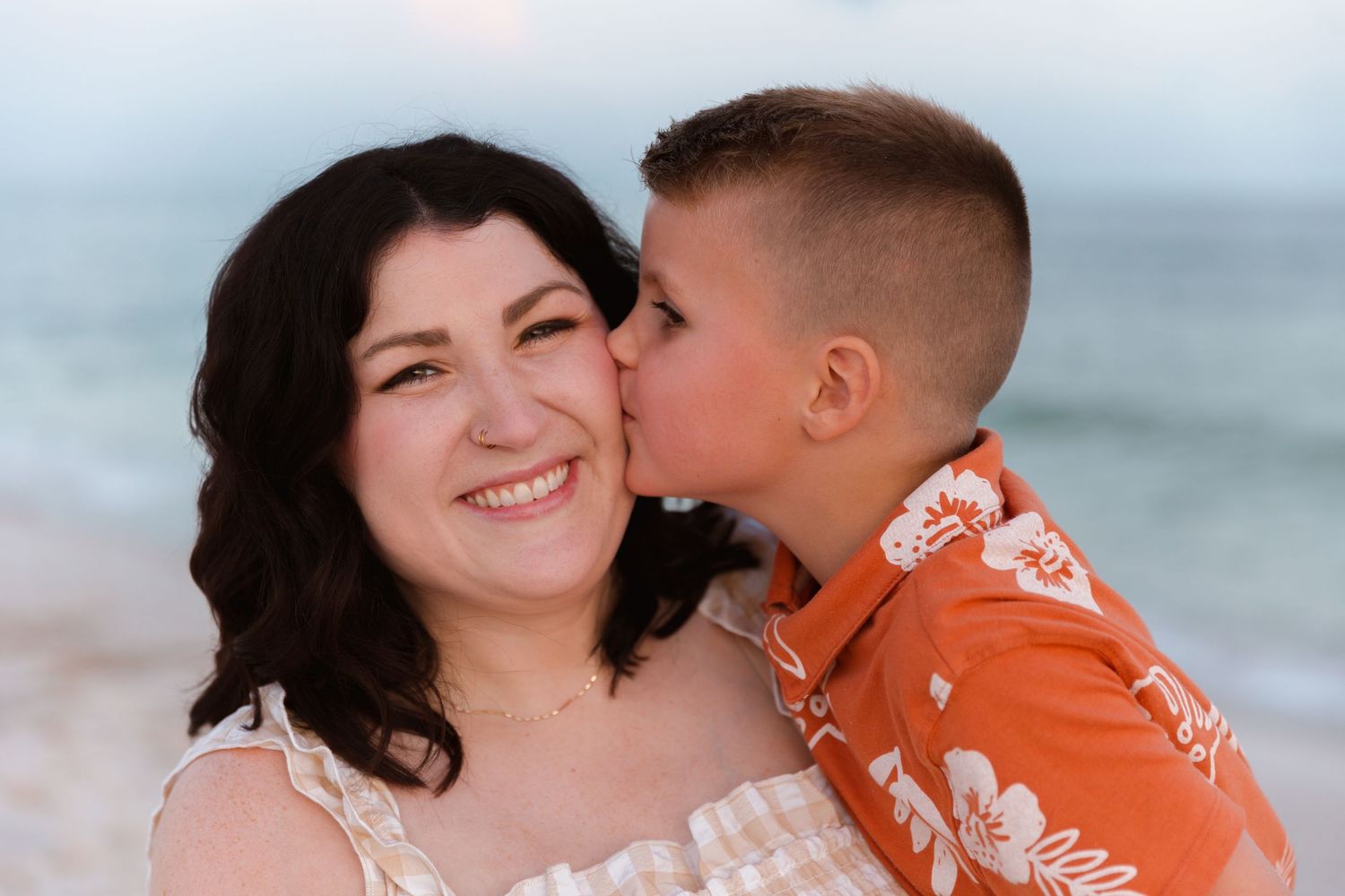A tender moment captured between two people against a blurred beach background during golden hour.