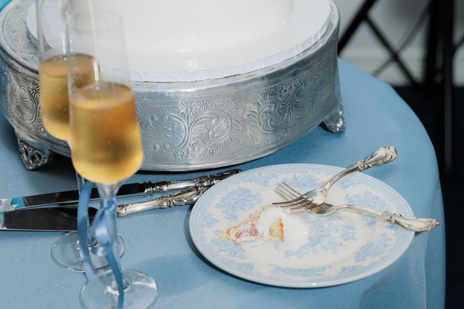 Empty wine glasses and dirty plates remain after a meal at restaurant table with white tablecloth.