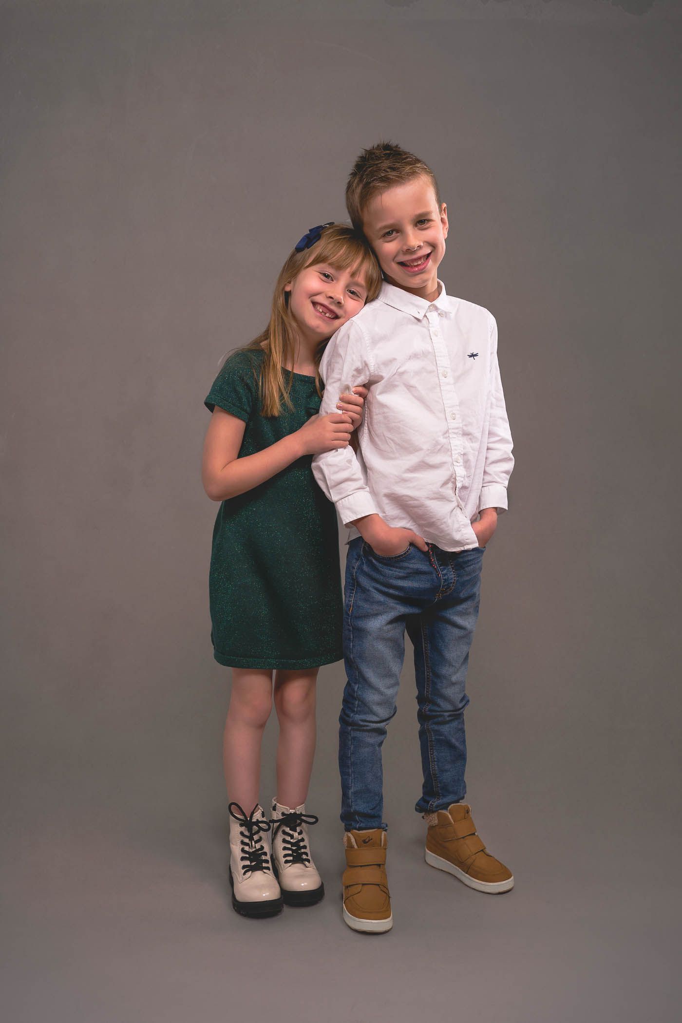 Little sister holding onto big brother's arm during a studio photoshoot