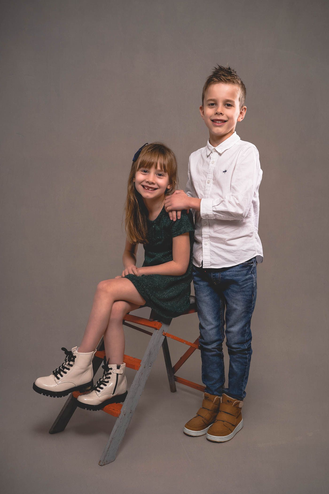 Little sister on a step ladder whilst big brother leans in during their studio photoshoot in Gloucester