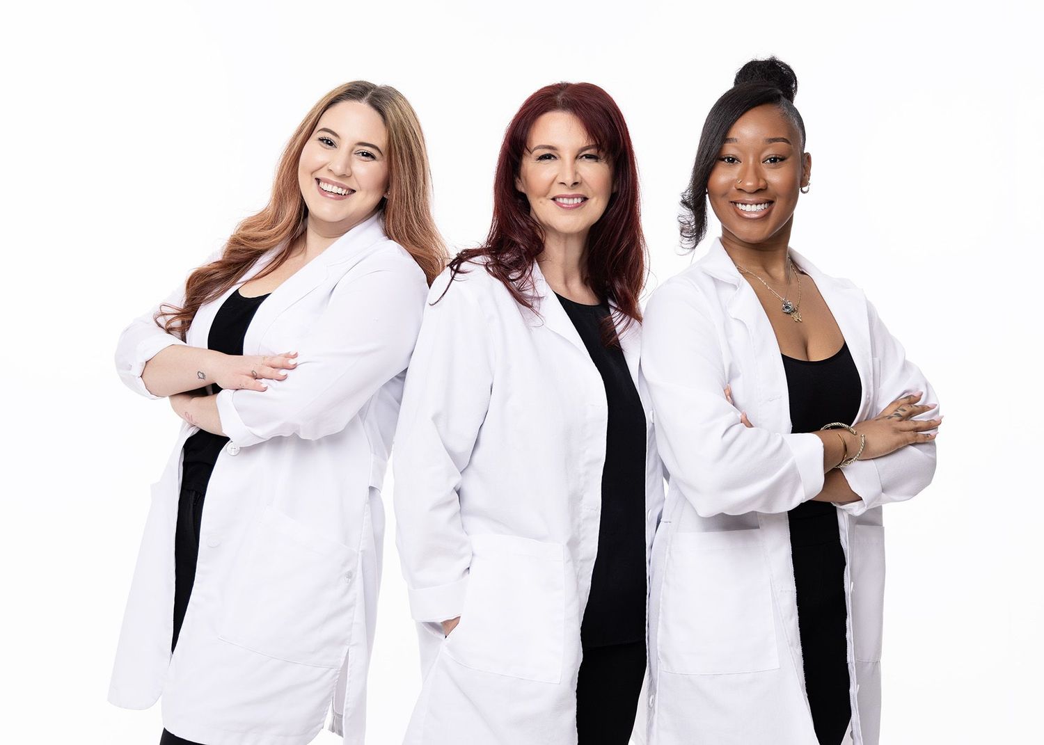 Group of medical professionals in white coats stand together smiling in a professional healthcare setting.