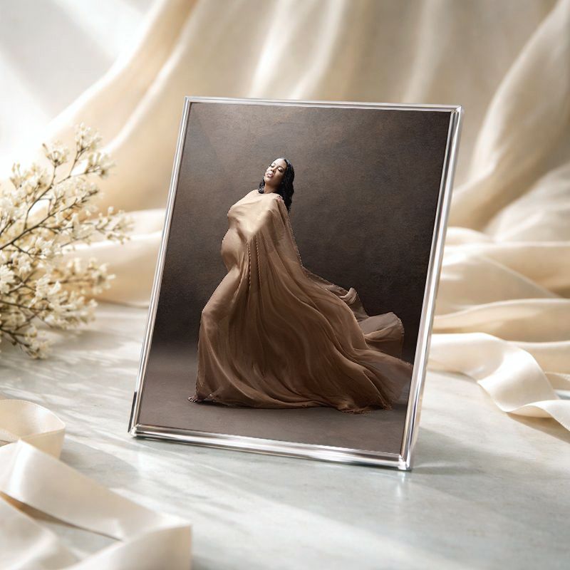 A series of elegant photos displayed on white fabric showing flowing dresses and delicate floral arrangements.