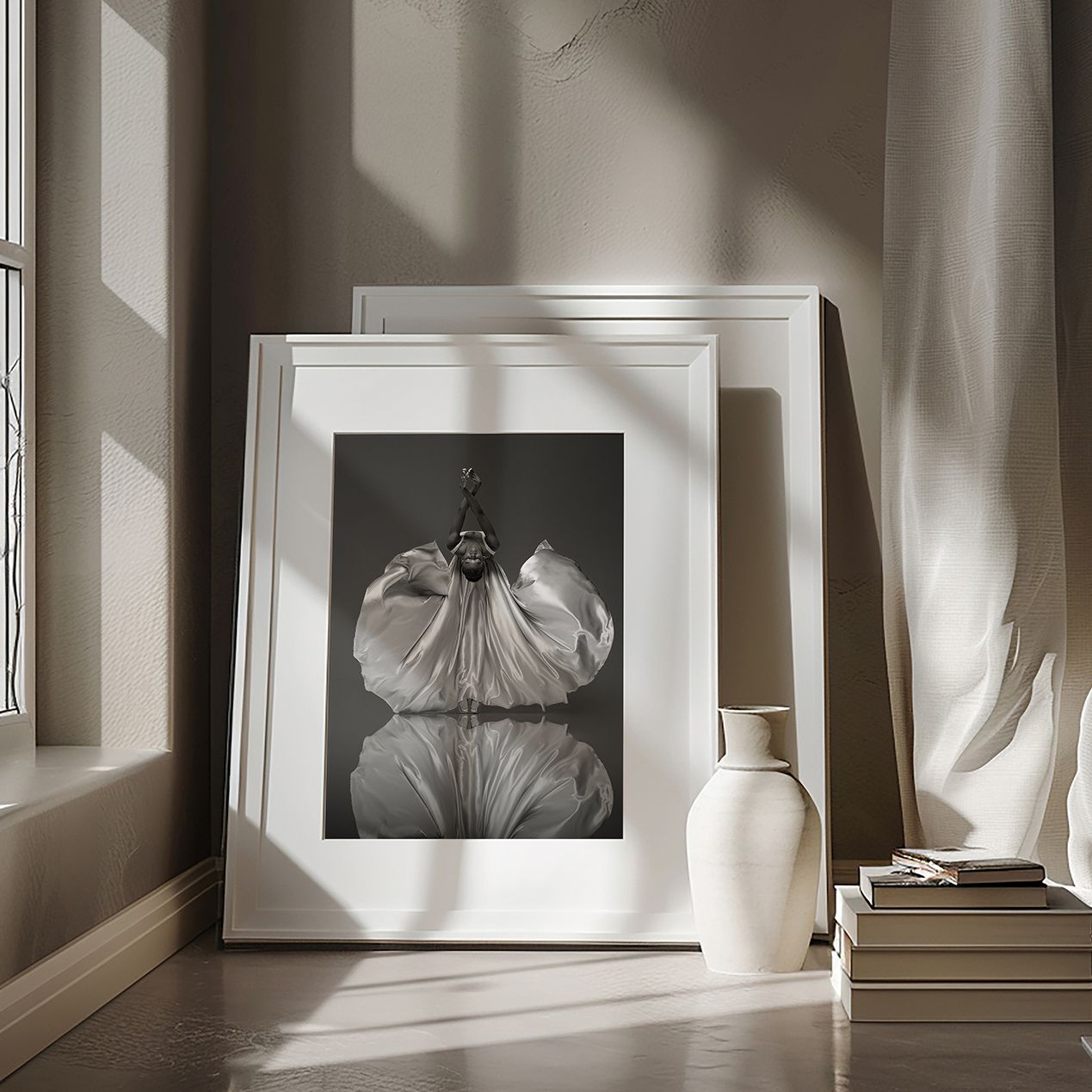 A gallery wall displaying black and white photographs and artwork in white frames against a neutral wall.
