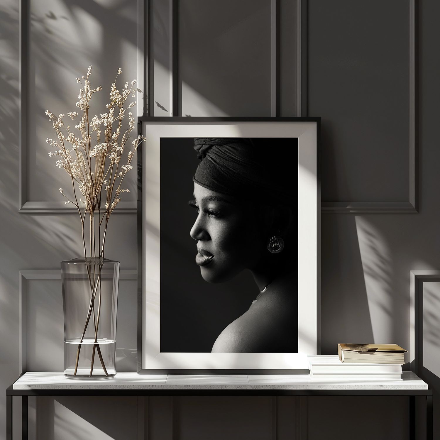 Black and white profile portrait of a woman in a framed art print displayed on a white shelf with dried flowers.