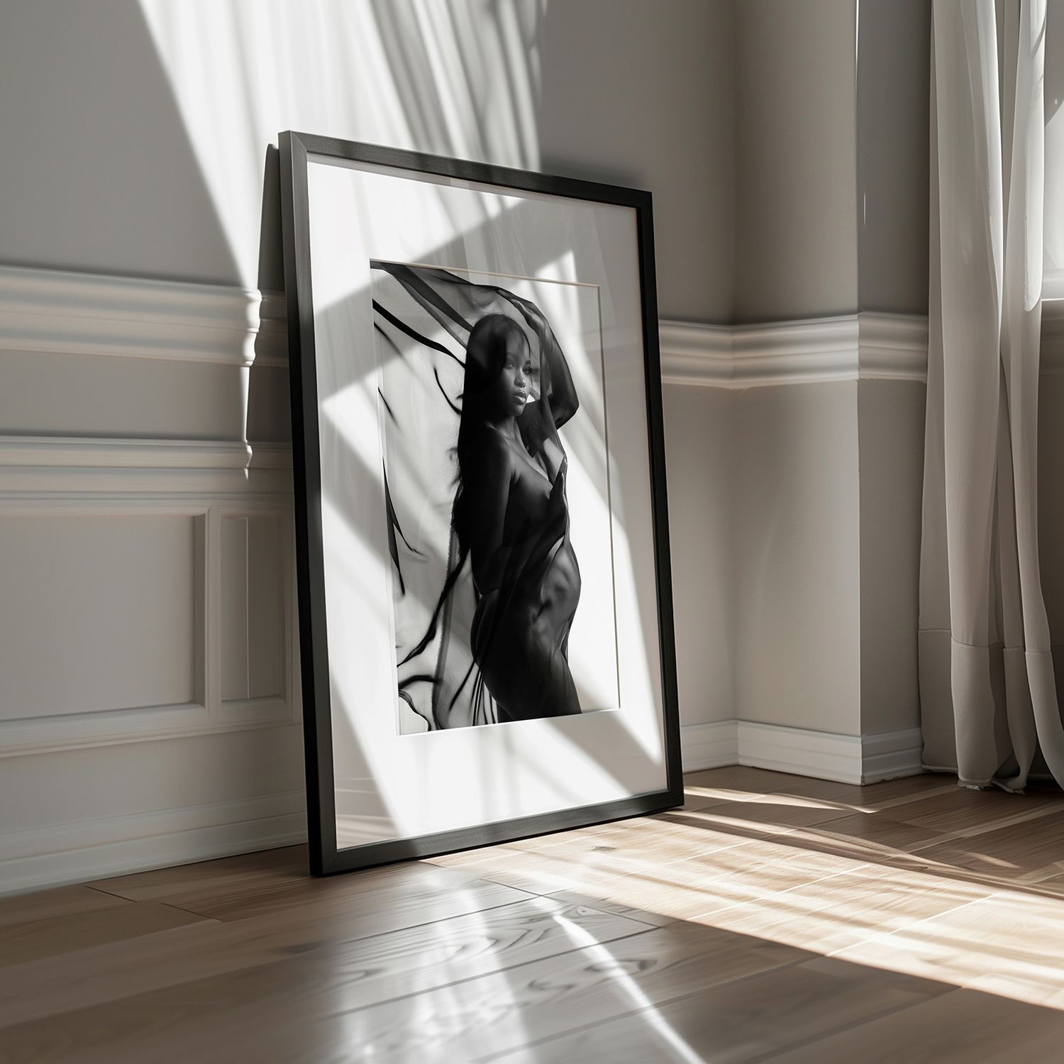 Black and white fine art print of a woman with flowing hair, framed and leaning against a wall in sunlit room.