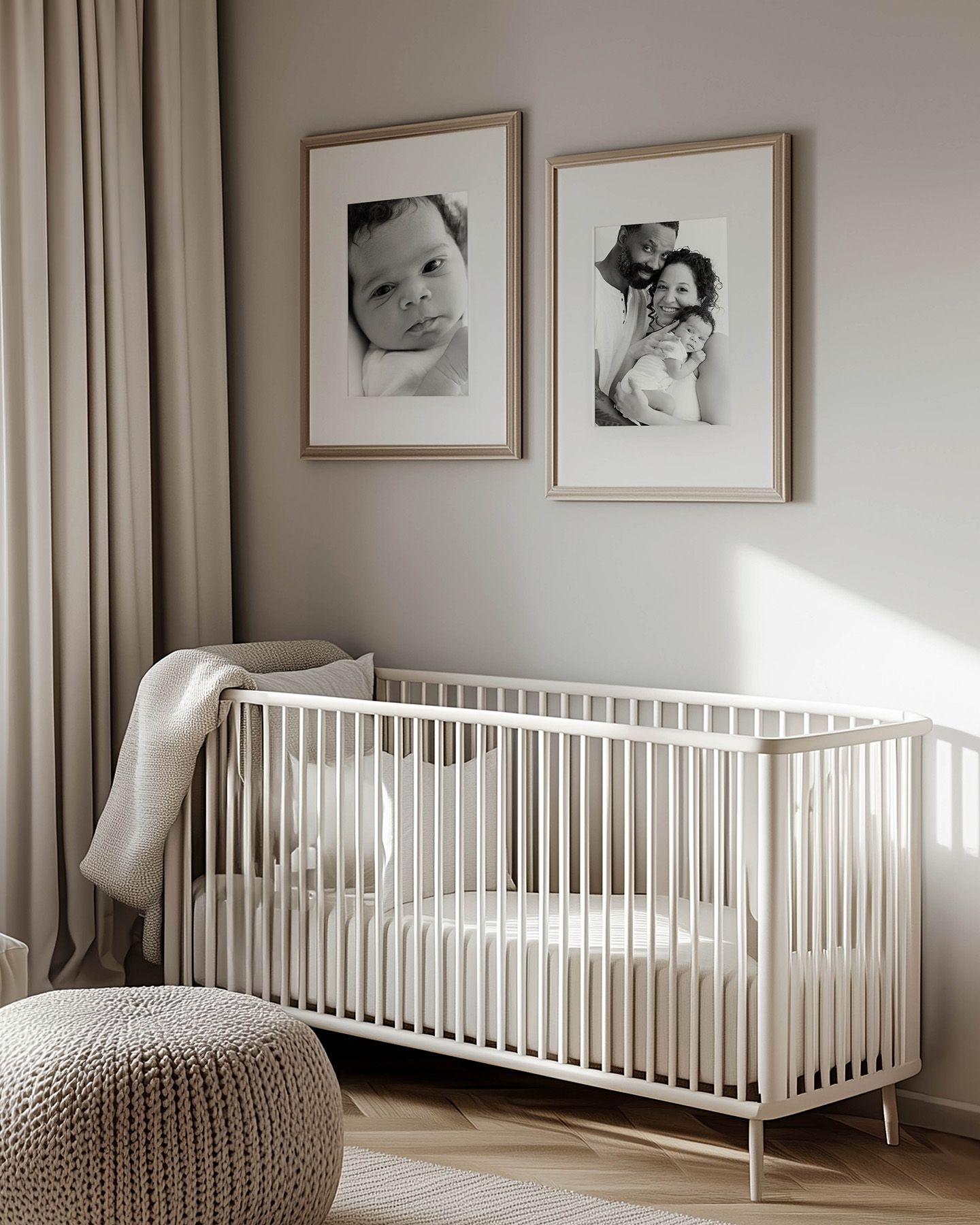 Minimalist nursery with white crib, knit pouf, neutral drapes, and two black-and-white baby photos in wooden frames above.