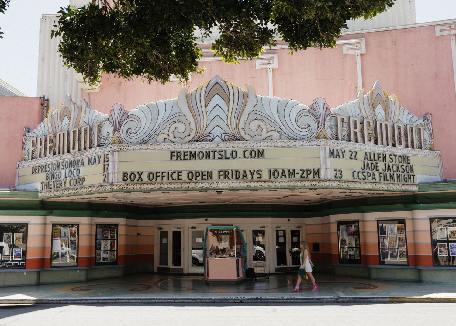 A Cal Poly SLO graduate walking in front of the Fremont Theater in Downtown San Luis Obispo, California.