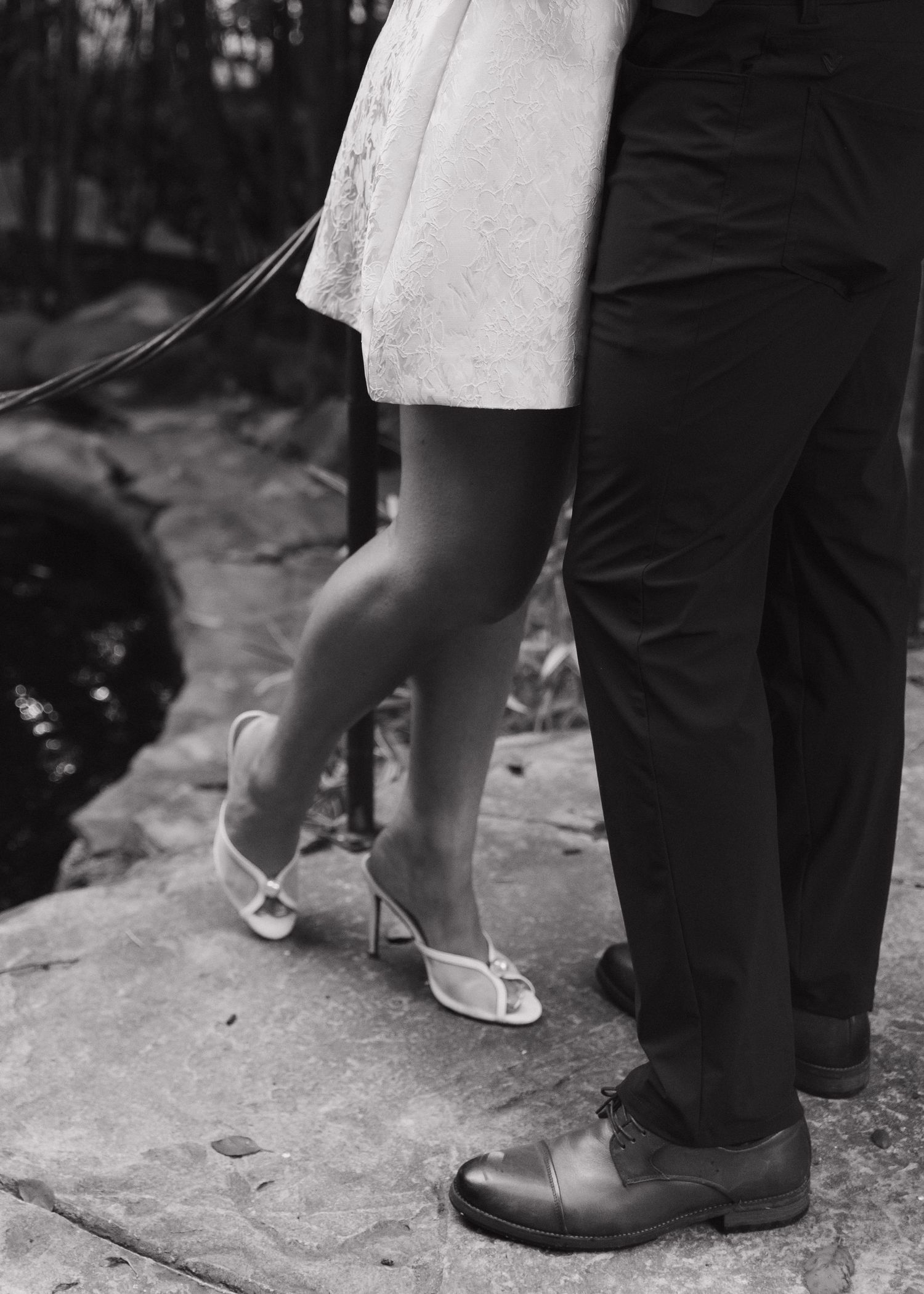 Black and white photograph showing close-up of feet and shoes of a couple standing on a stone surface at Hartley Botanica in Camarillo, CA.