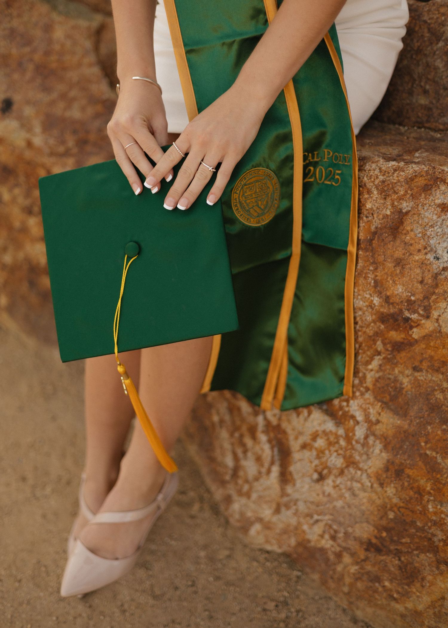 Close-up view of a Cal Poly San Luis Obispo graduate's stole, cap, and heels.