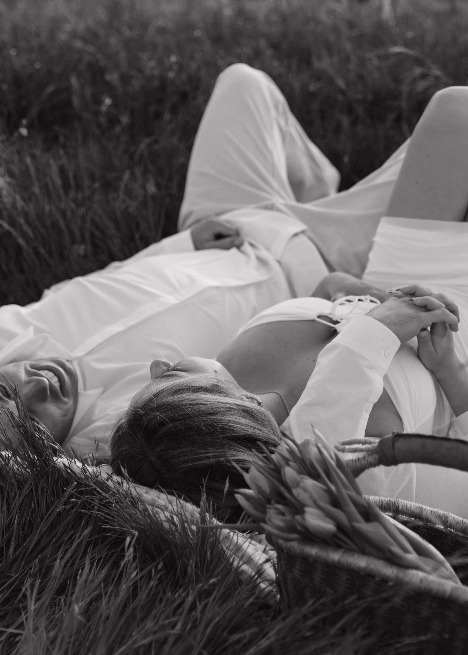 Black and white photograph of people lying in tall grass at the dreamy Prefumo Canyon in San Luis Obispo.