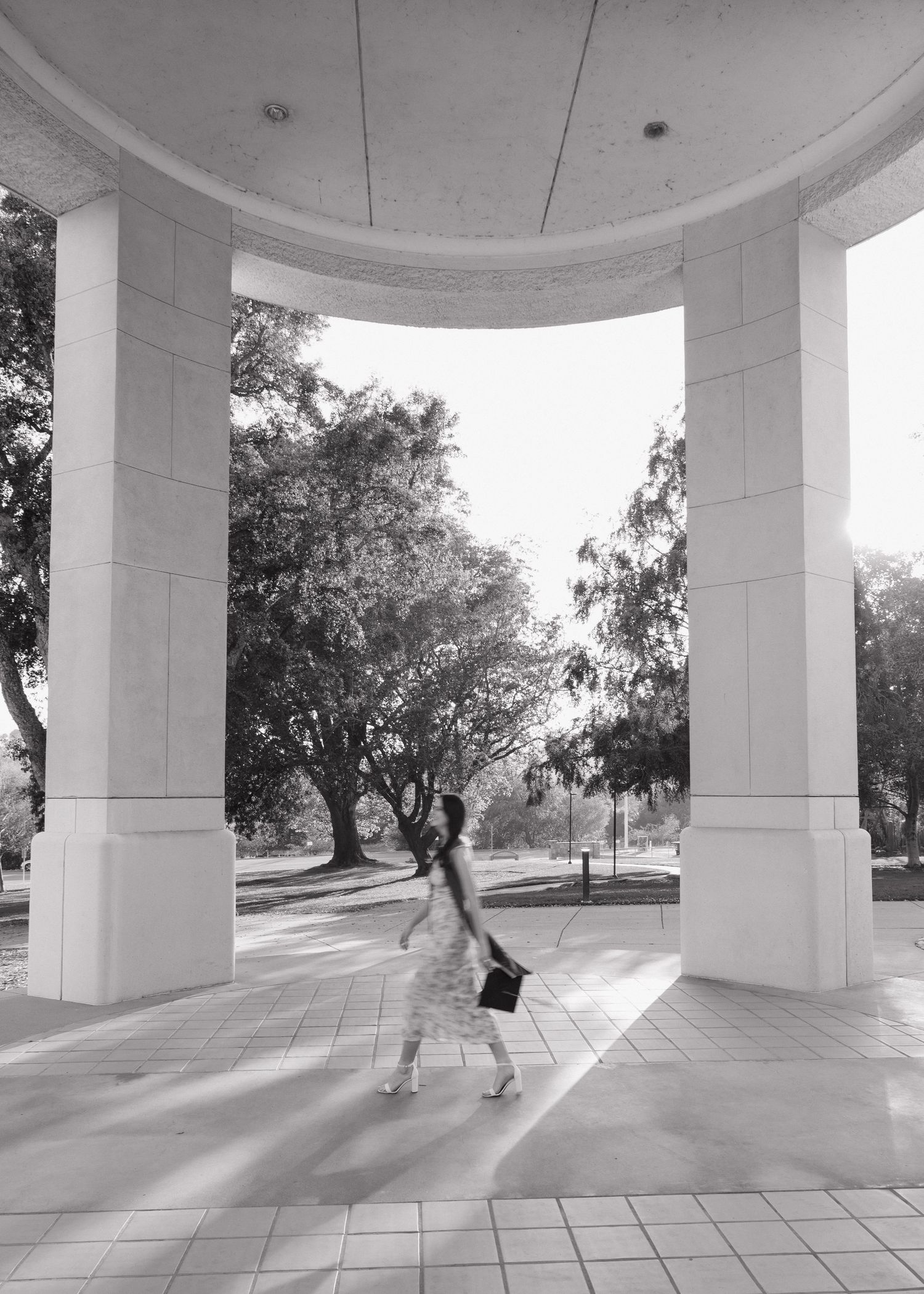 A Cal Poly San Luis Obispo graduate walking blurry between two posts at the Orfalea College of Business.
