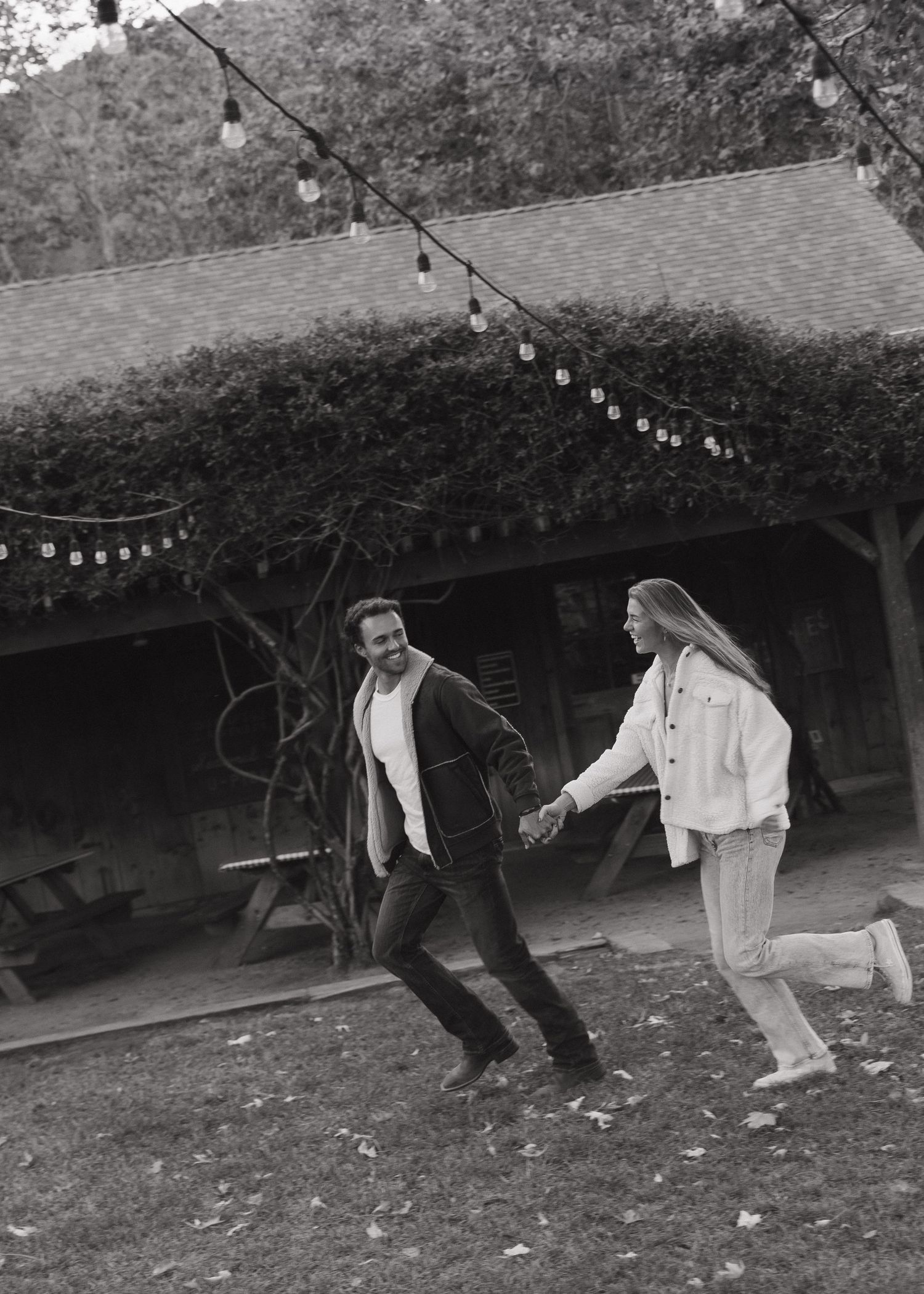 A couple running hand in hand outdoors under string lights at Avila Valley Barn in California.