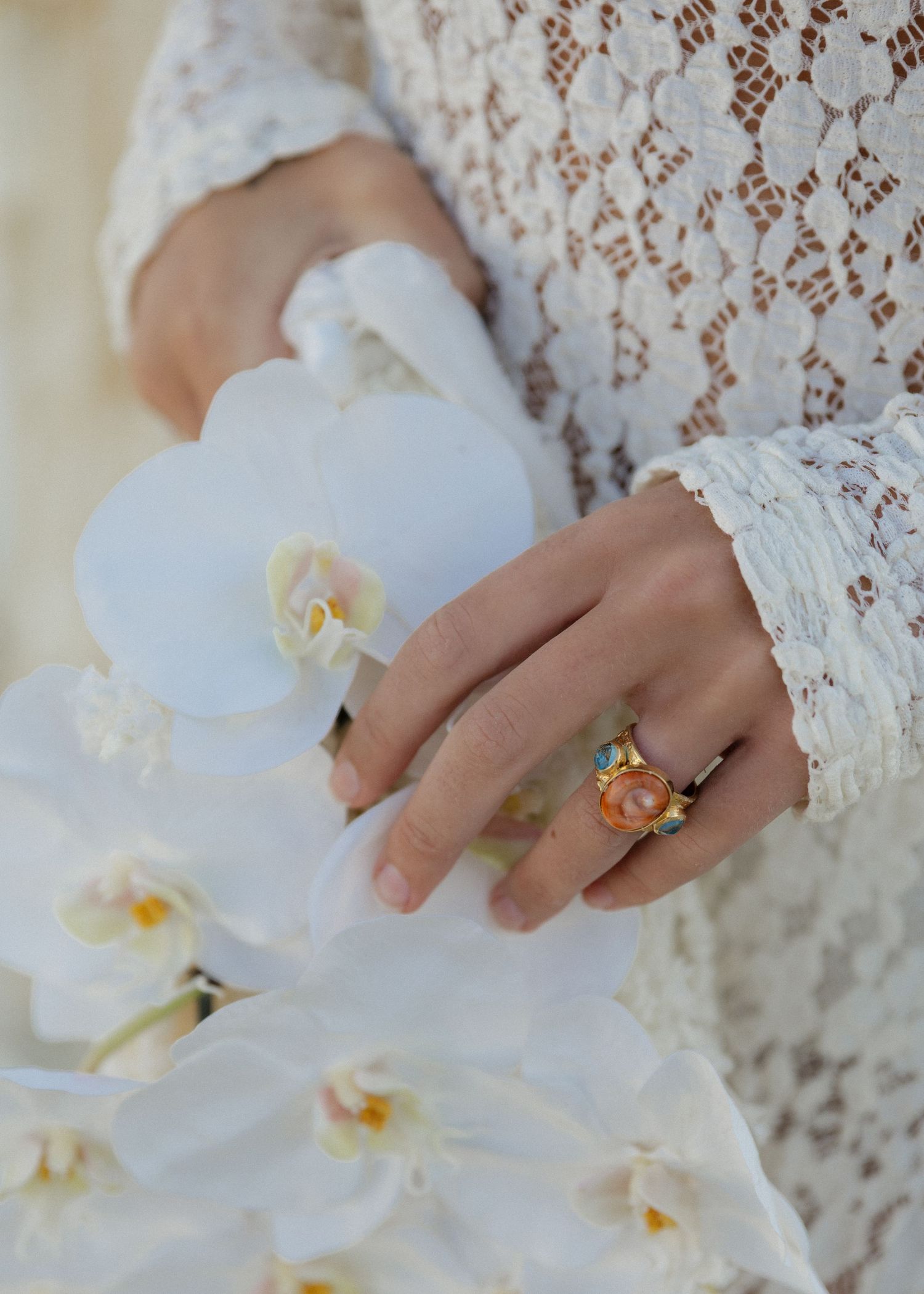 Delicate white orchid wedding bouquet being gently held by a brides hand wearing a vintage engagement ring.