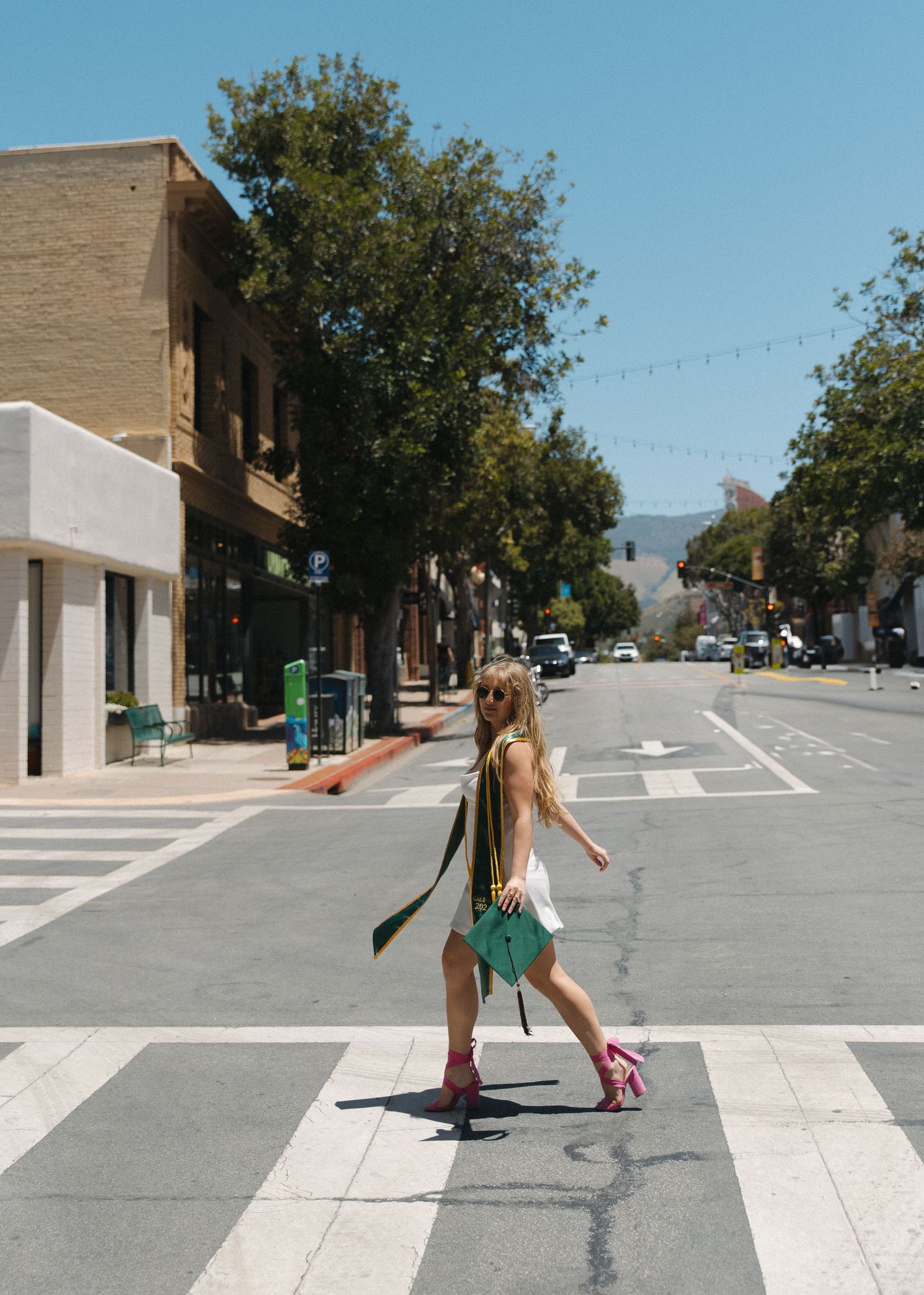 Sequential shots showing someone crossing an empty urban street intersection on a sunny day.
