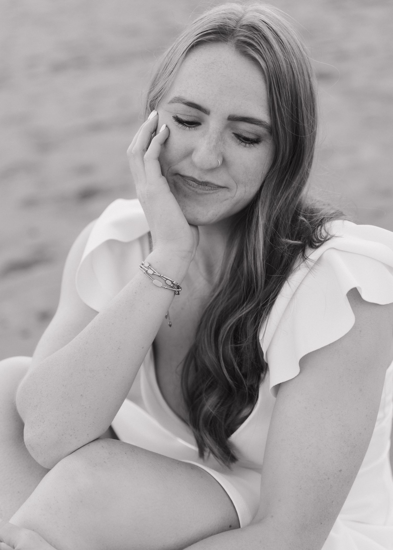 A Cal Poly San Luis Obispo graduate poses for a candid black and white portrait while smiling.