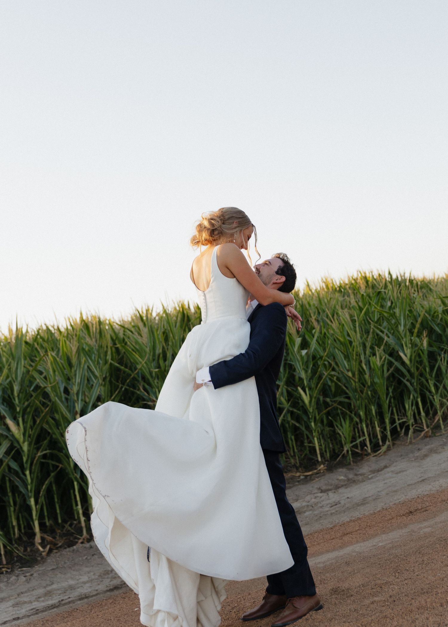 A portrait of groom picking up a bride during golden hour.