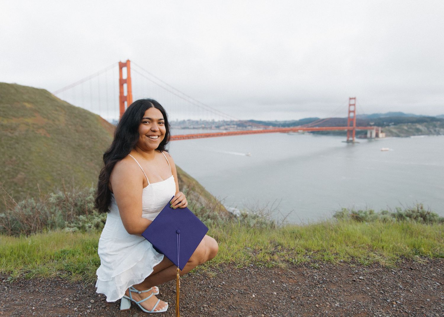 A San Francisco State University graduate poses with the Golden Gate bridge in the backdrop