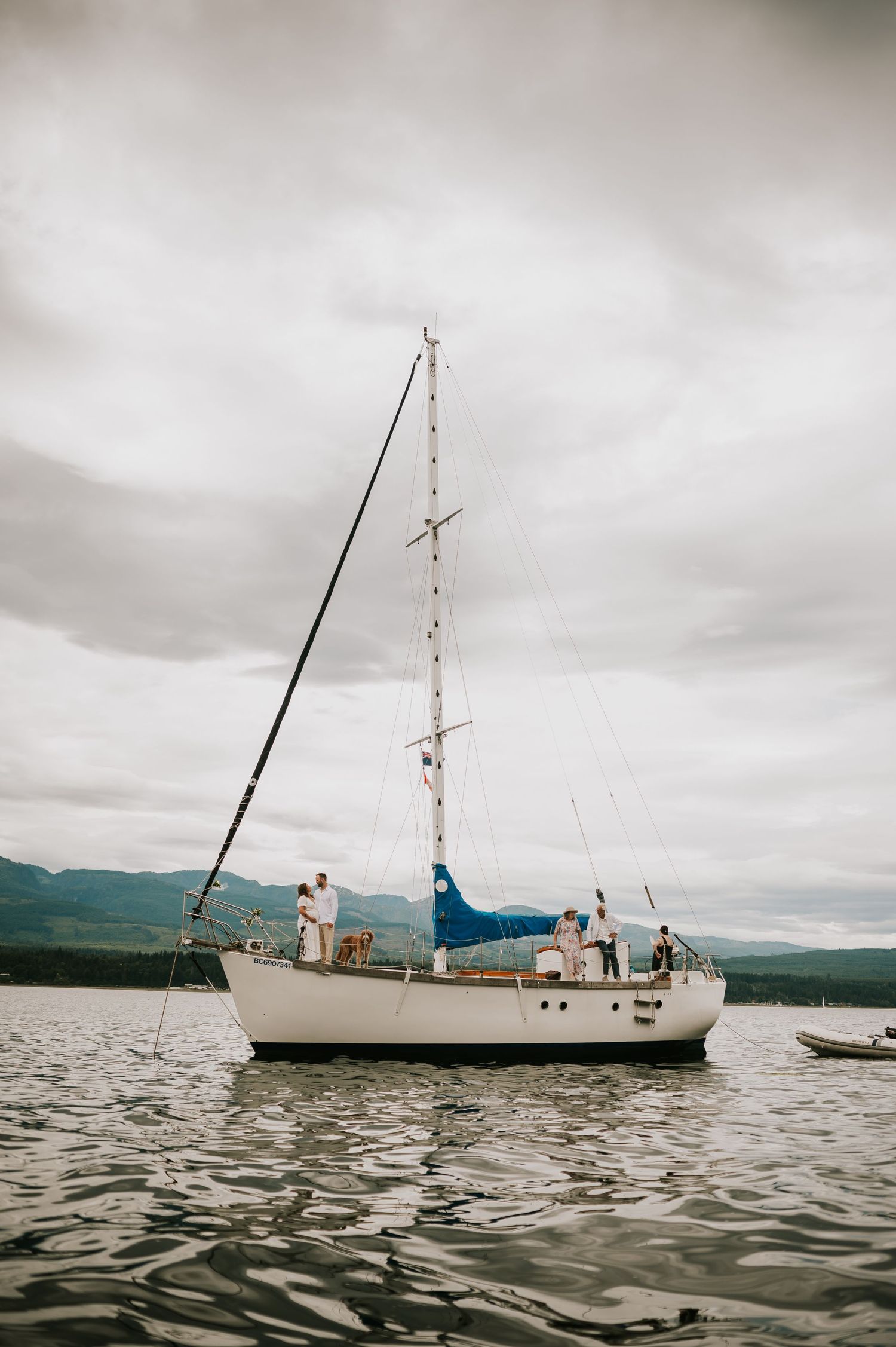 Comox Valley Sailboat Elopement of boat in ocean beside Denman Island with wedding couple. Photographer in boat taking portraits of boat