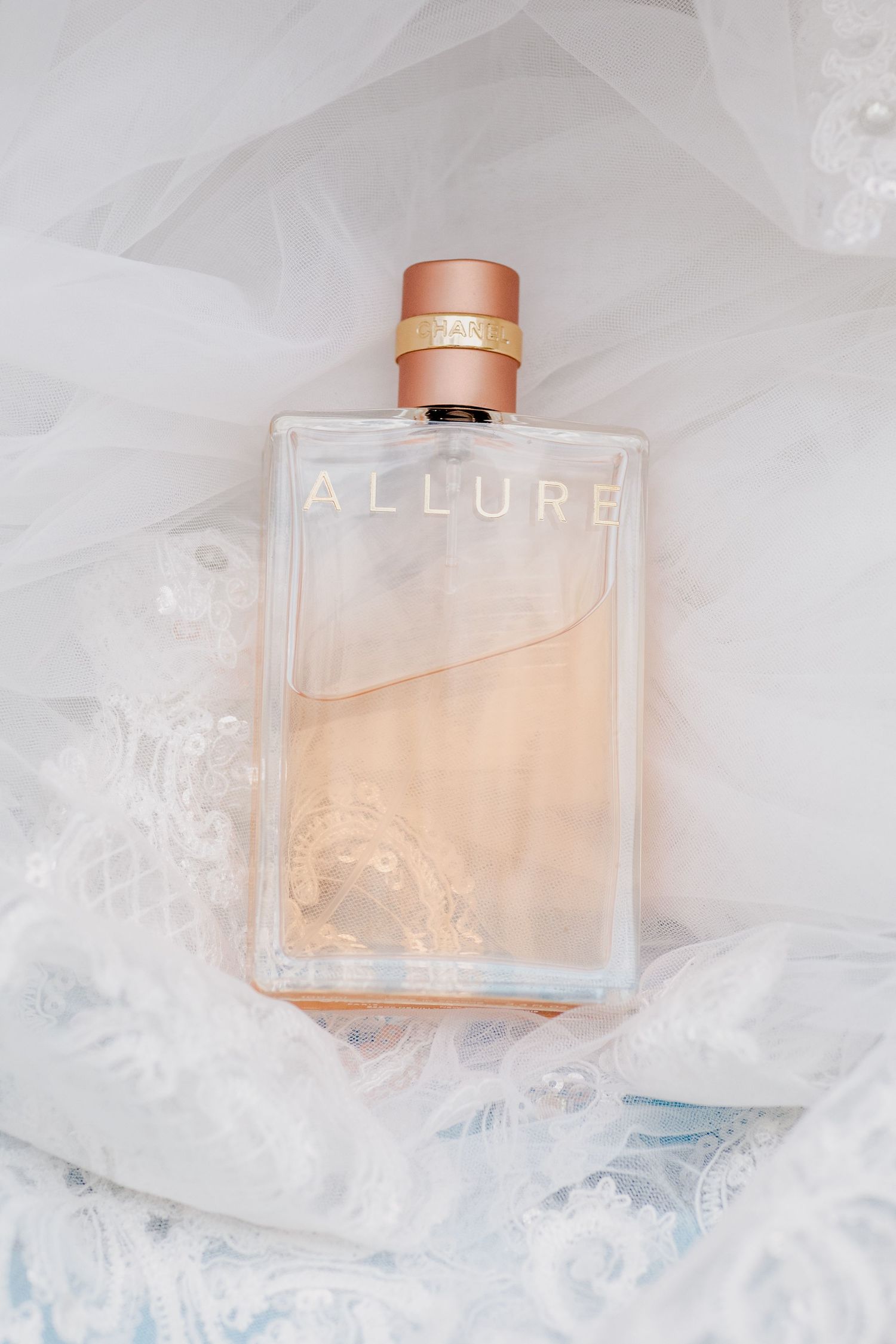 Chanel Allure perfume bottle nestled in soft white tulle fabric.