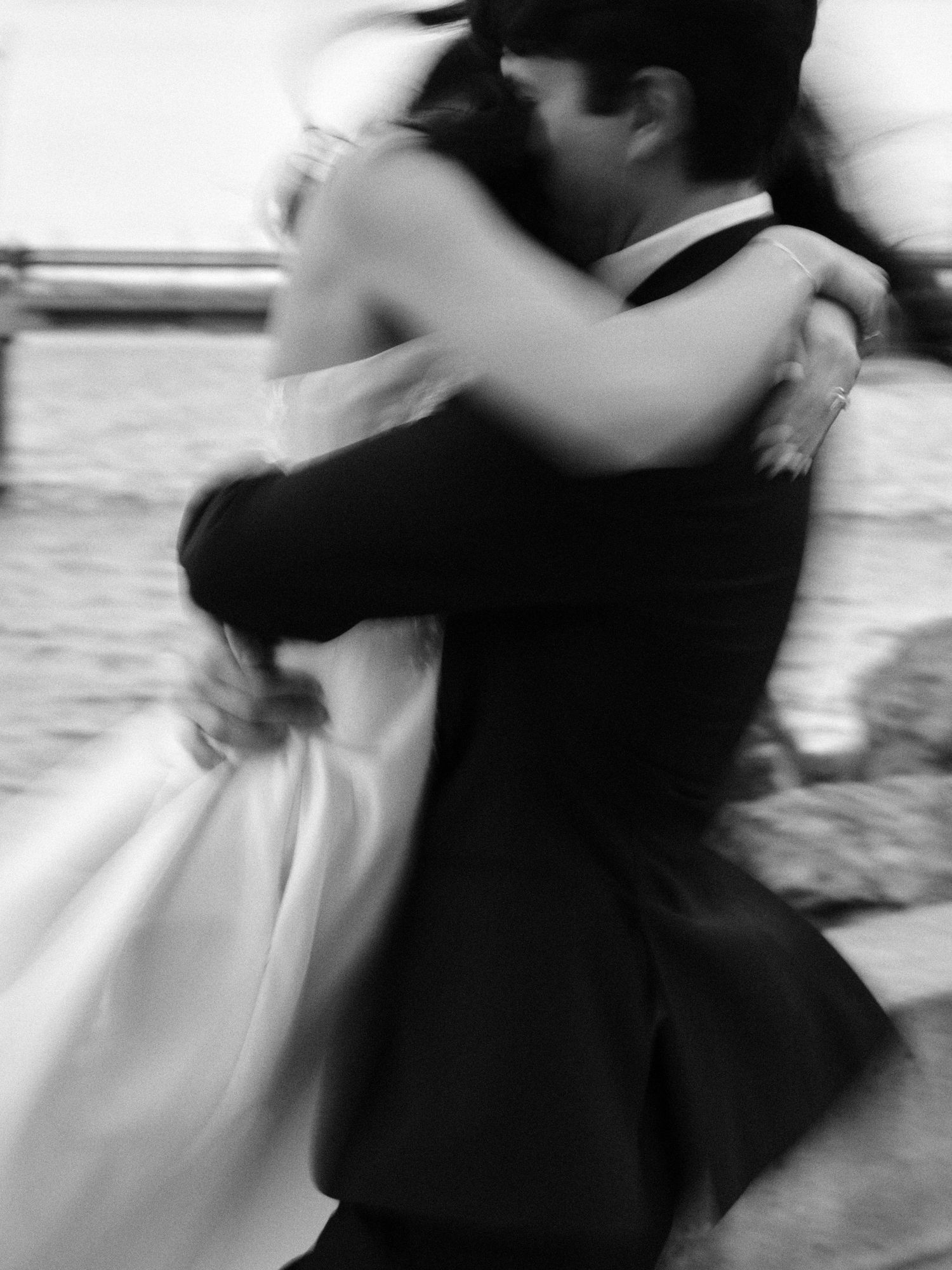 Blurred motion black and white photo of dancing couple in formal attire.