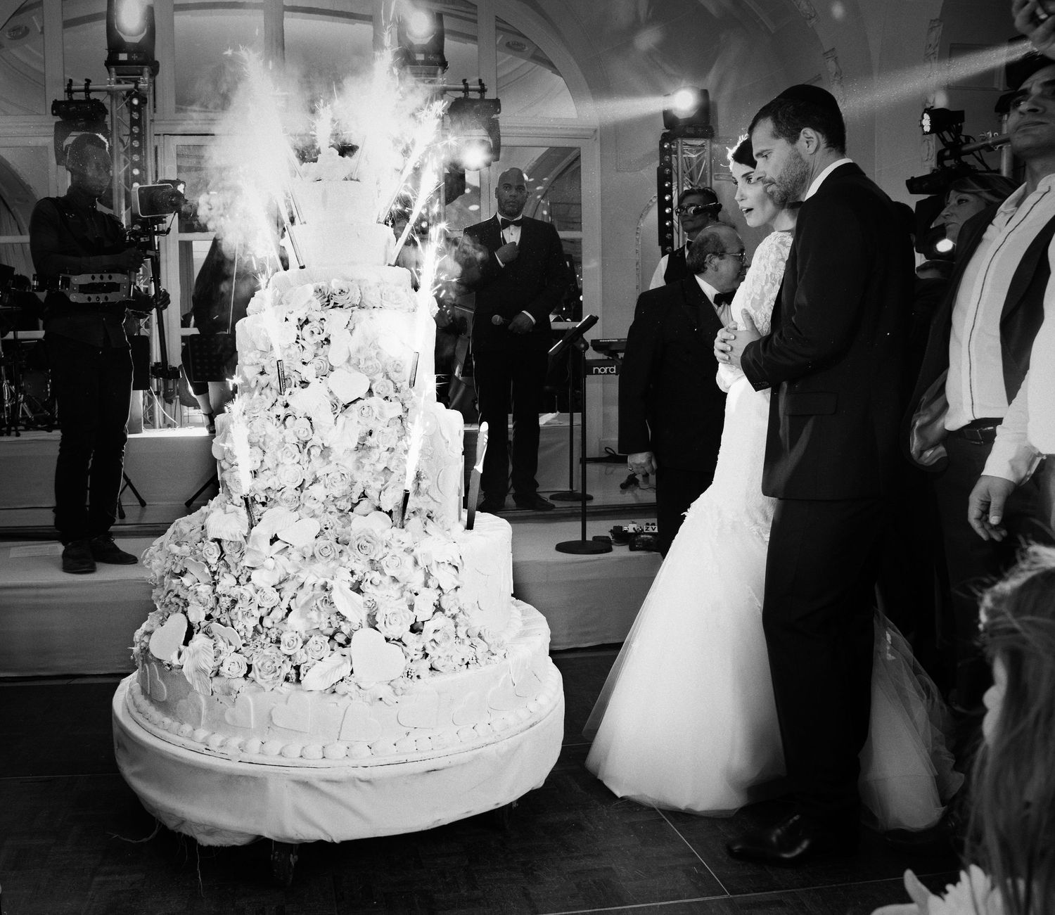 Wedding reception scene with an elaborate white tiered cake and dancing couple.