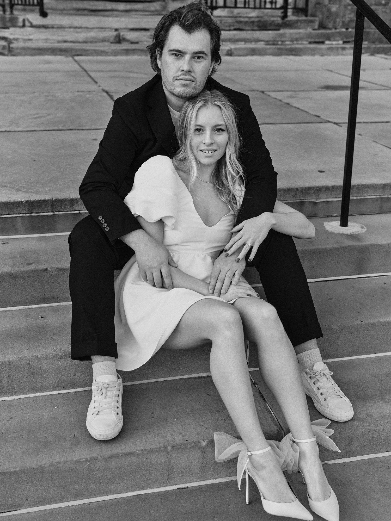 A casual portrait of a couple sitting on stone steps outdoors.