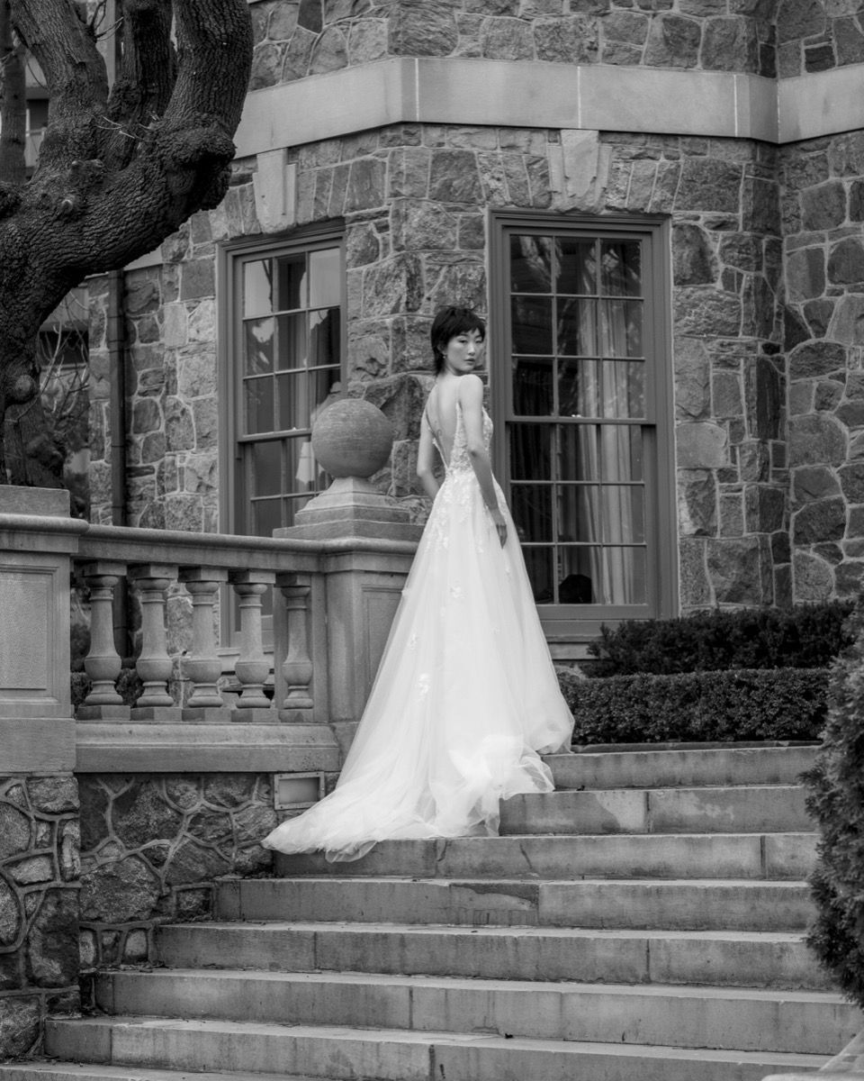 Black and white photo of wedding gown on stone mansion steps.