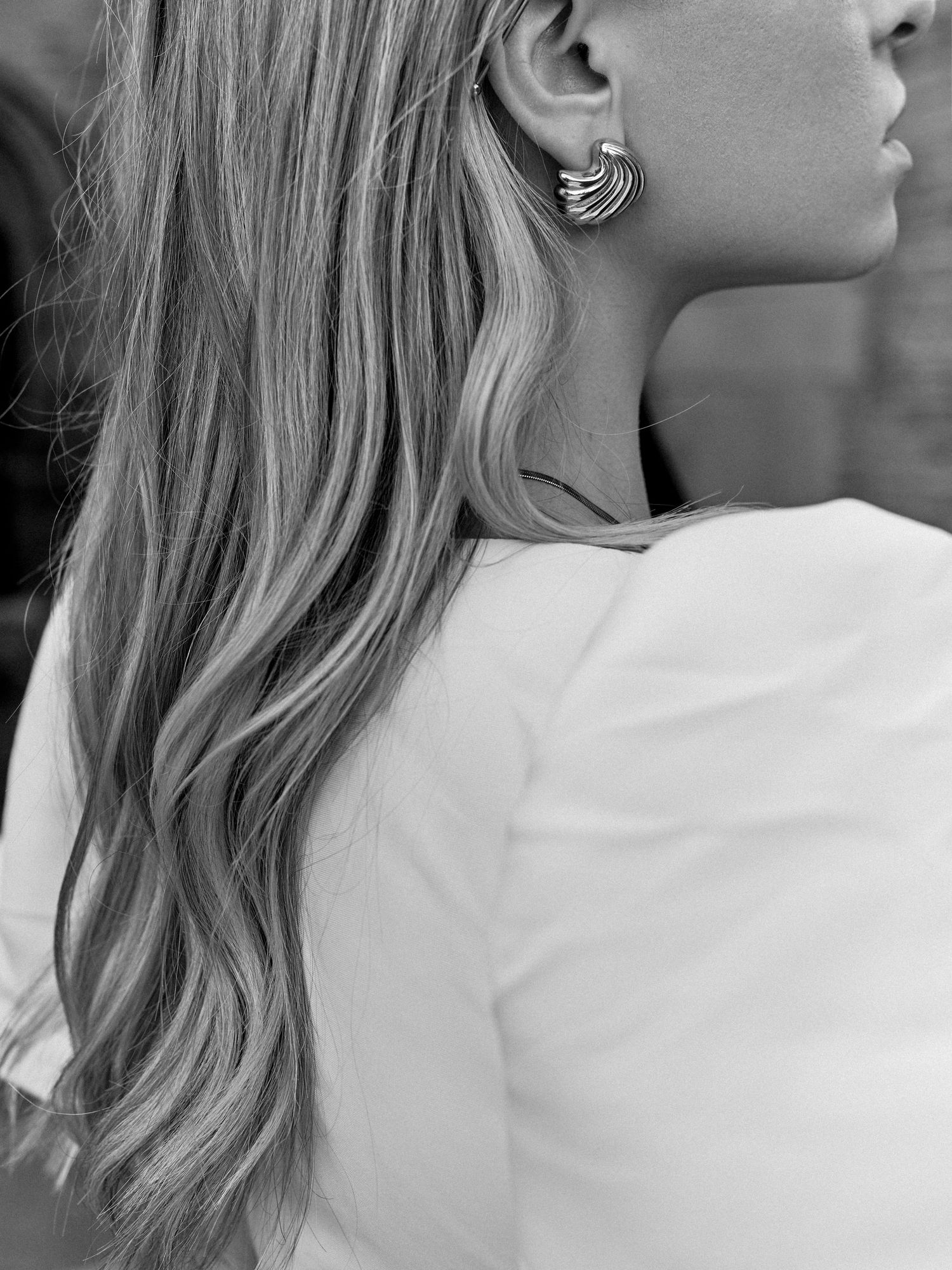 Close-up black and white portrait showing blonde hair and decorative ear cuff jewelry.
