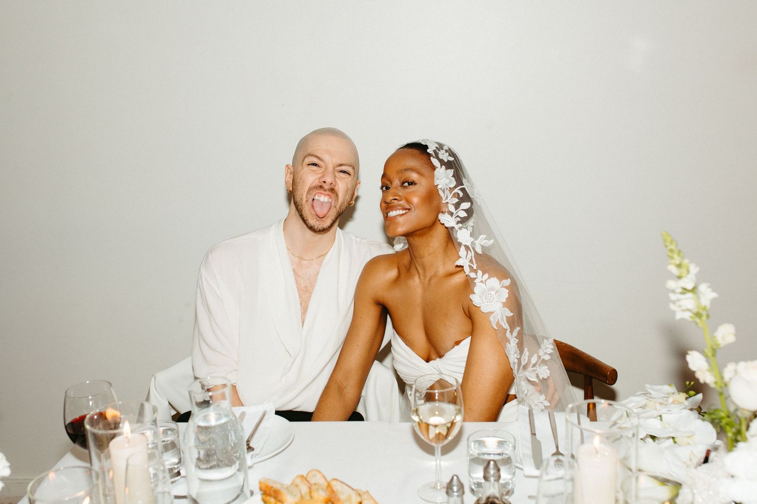 Candid reception photo of newlyweds laughing together at dinner table.