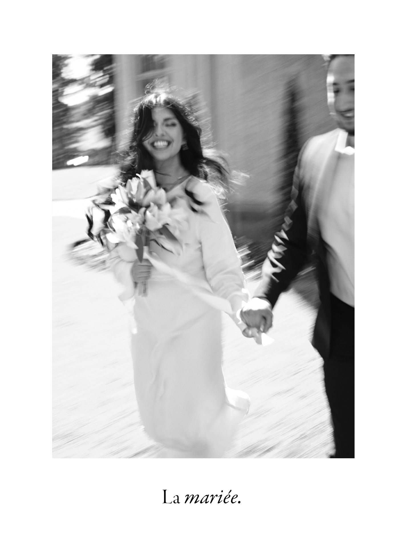 A black and white motion shot of a joyful bride running while holding her bouquet.
