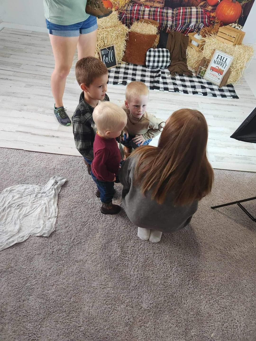 Children gather around to look at something on the carpeted floor.