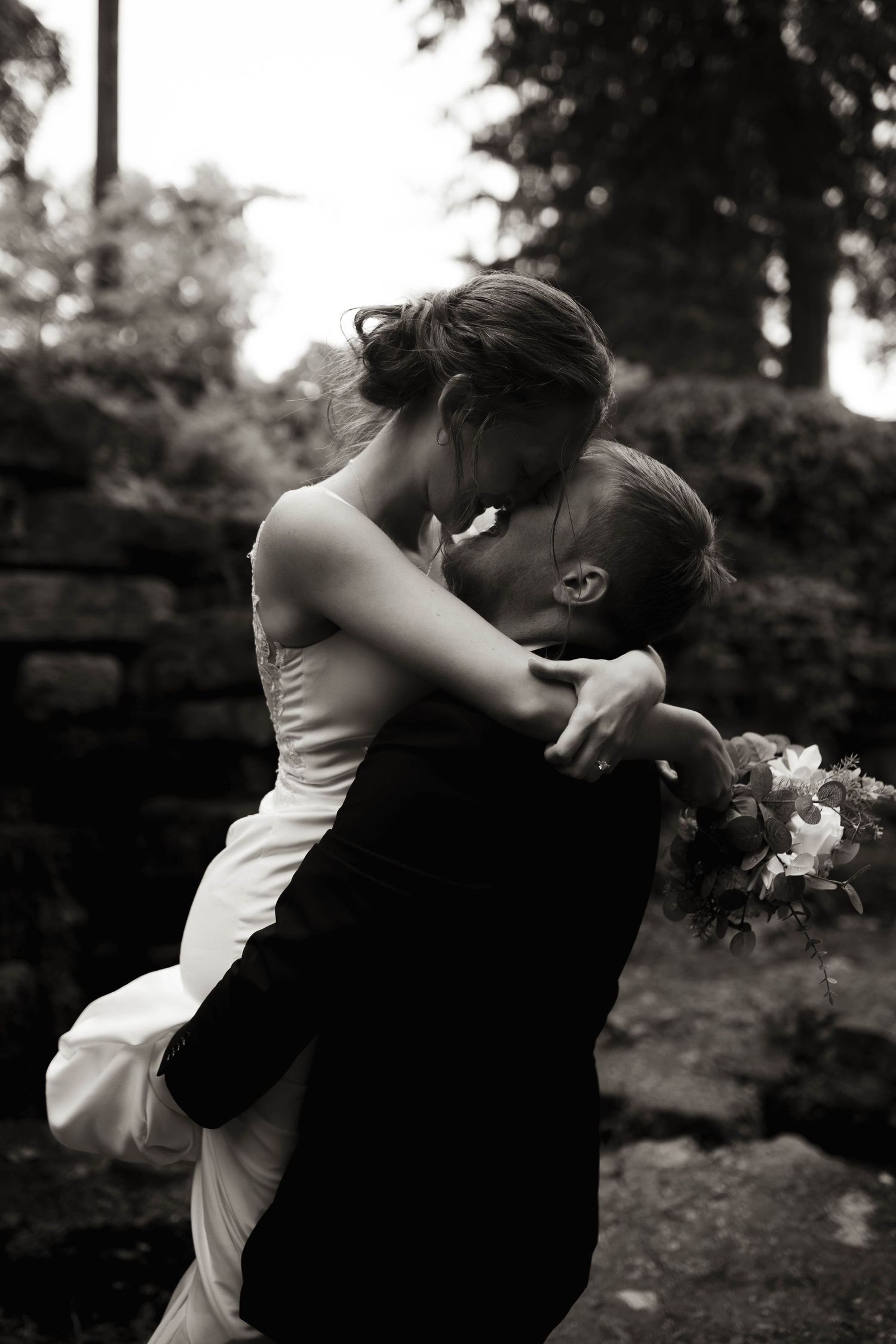 Black and white photo series captures a couple's romantic embrace in a garden setting.