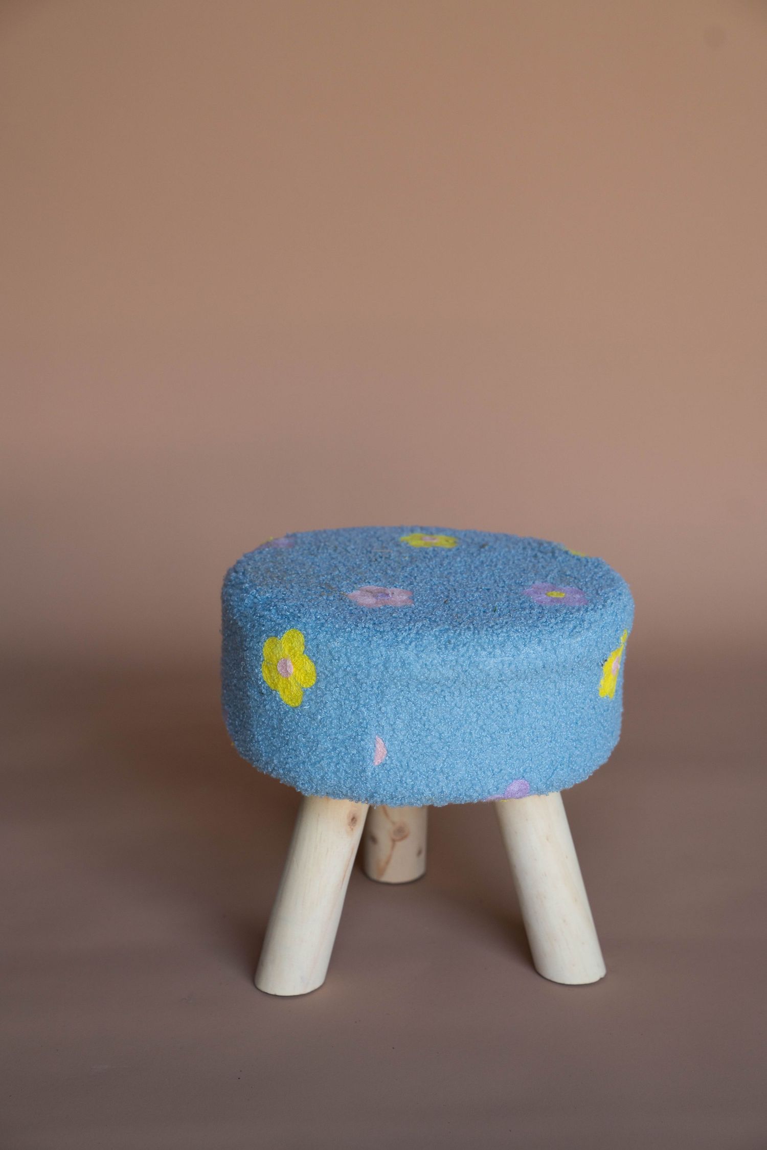 Small blue cushioned footstool with decorative patterns shown from multiple angles.