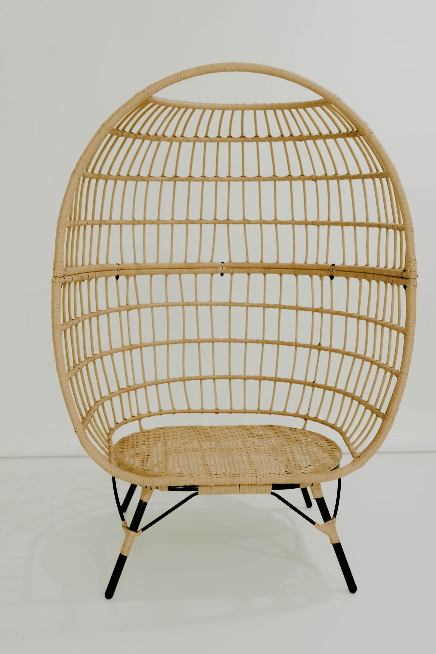 Modern rattan bench with curved dome shape and black metal legs against white background.
