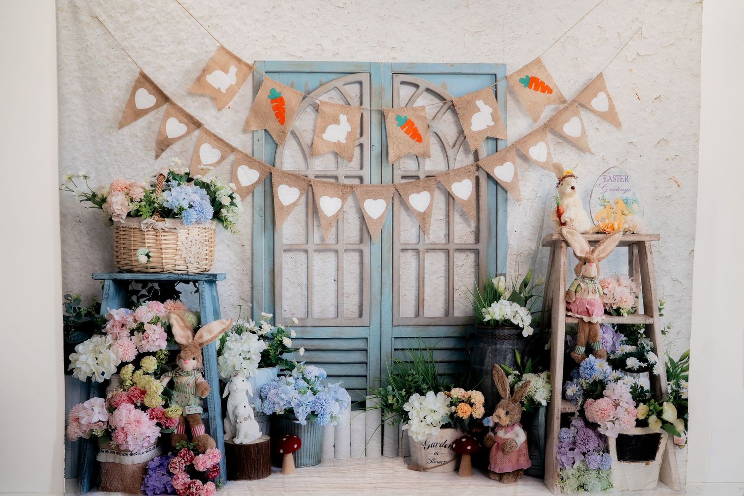 Vintage-style party setup with blue doors, floral arrangements, and bunting decorations.