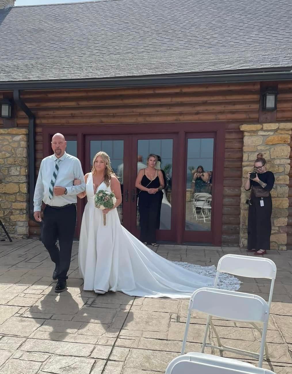 A wedding ceremony setup with white chairs and stone architecture in an outdoor venue.