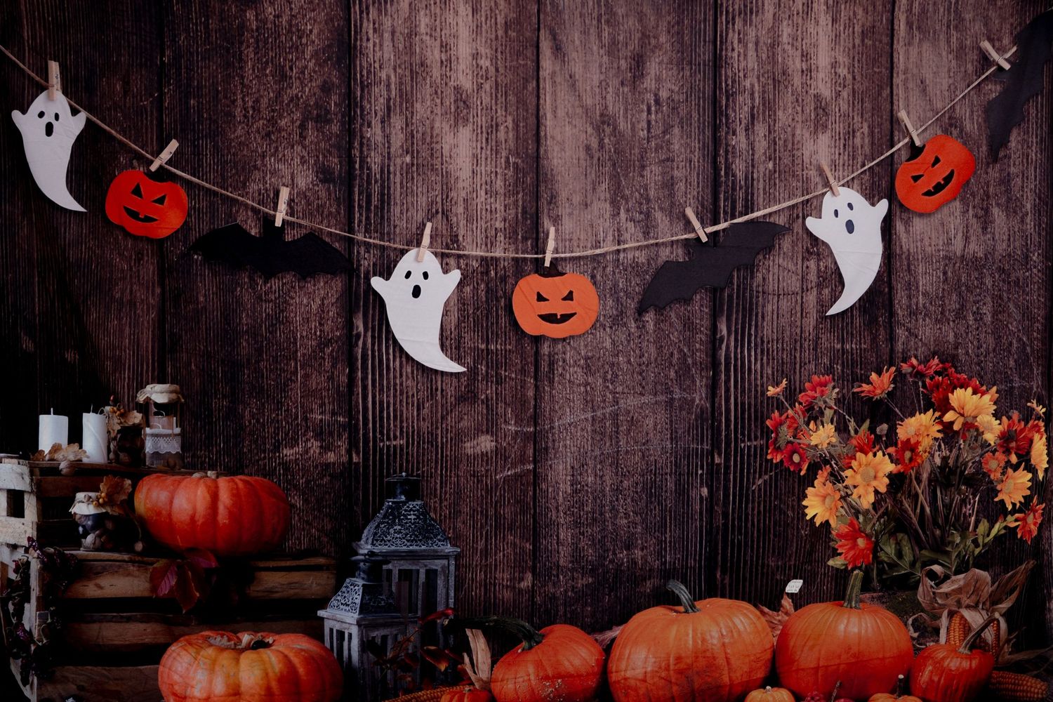 Rustic wooden backdrop decorated with Halloween ghost and pumpkin garland.